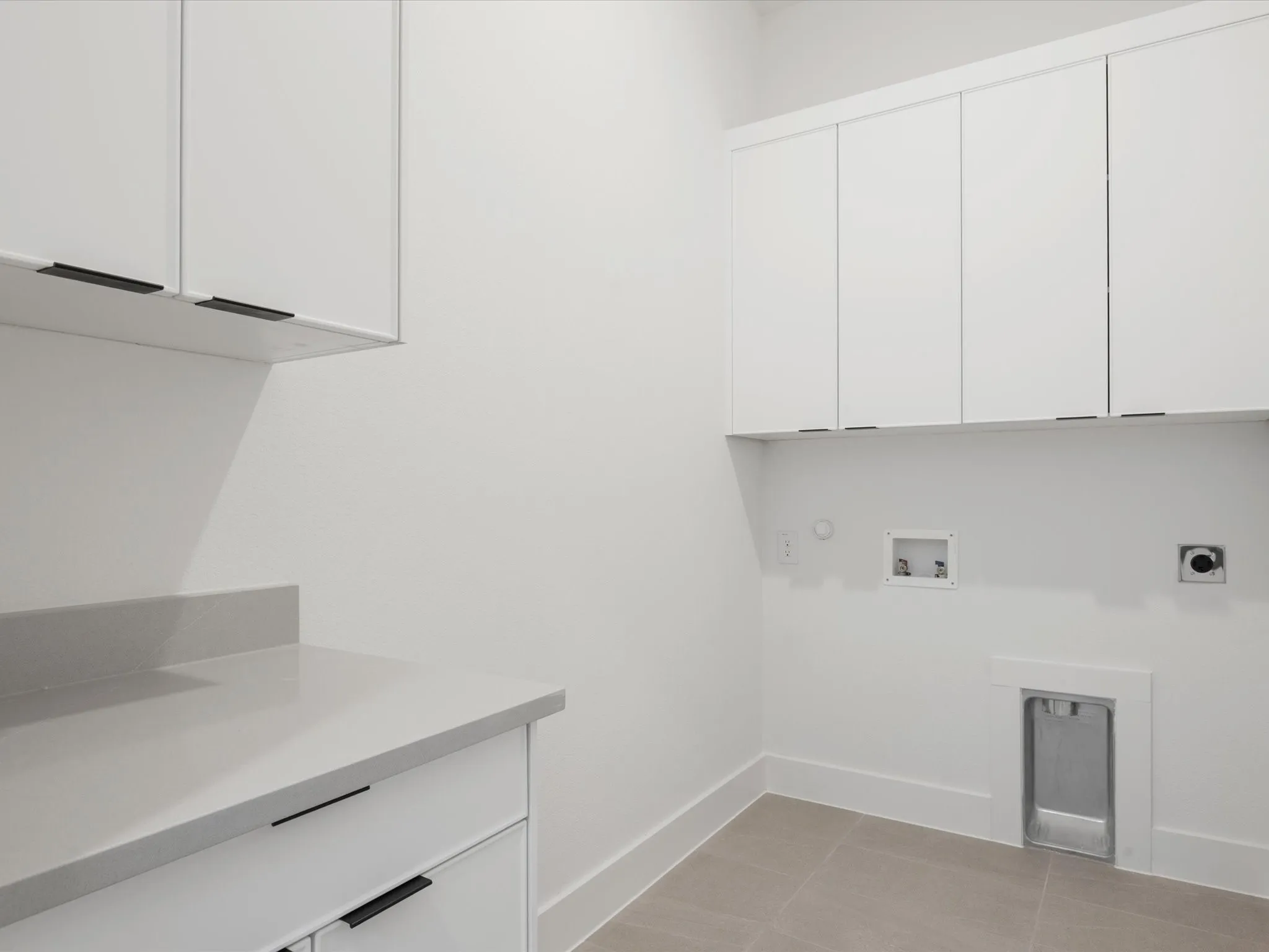 Washroom with cabinet space, washer hookup, hookup for an electric dryer, light tile patterned floors, and hookup for a gas dryer