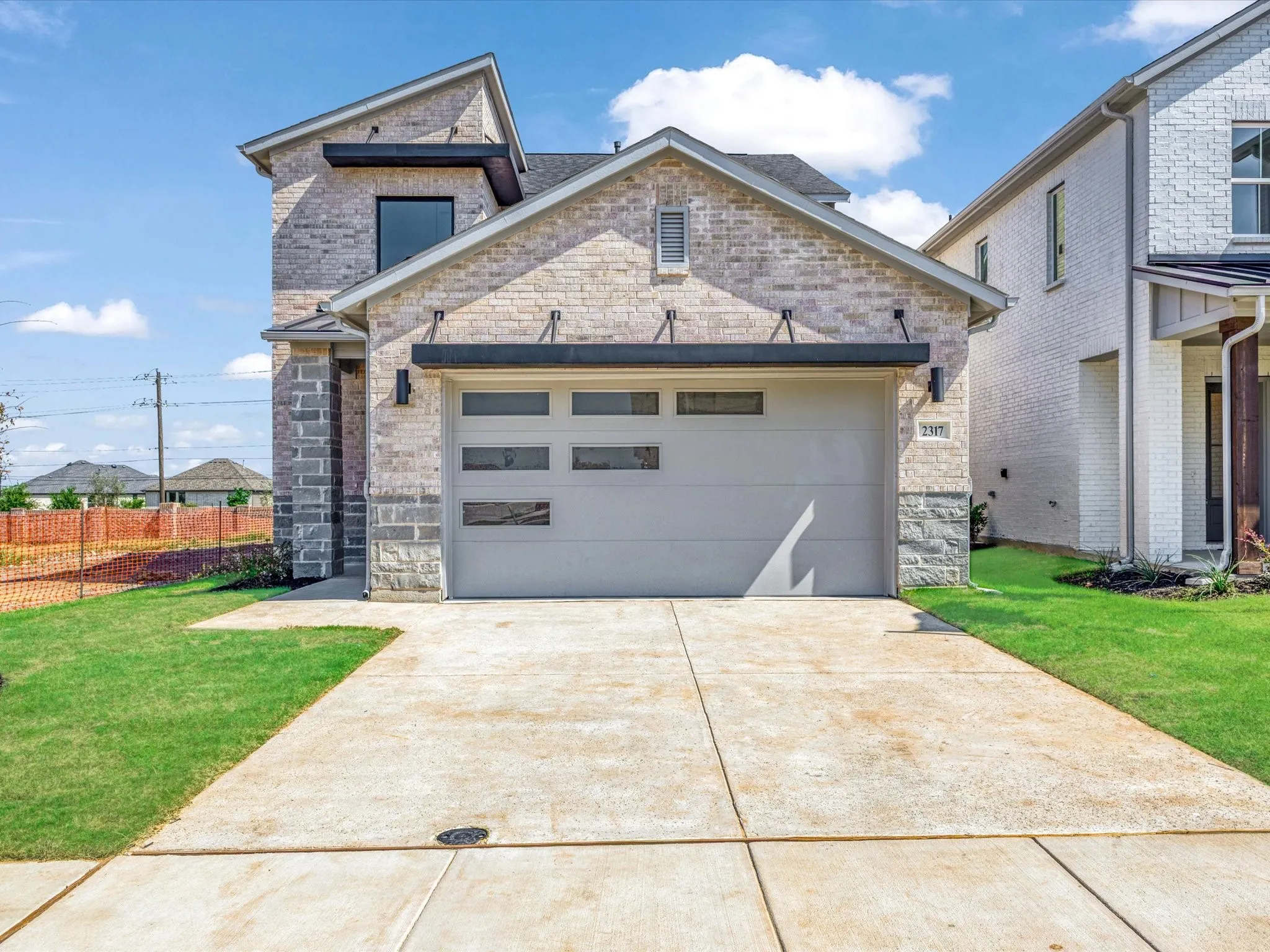 View of front of house with an attached garage, concrete driveway, and stone siding