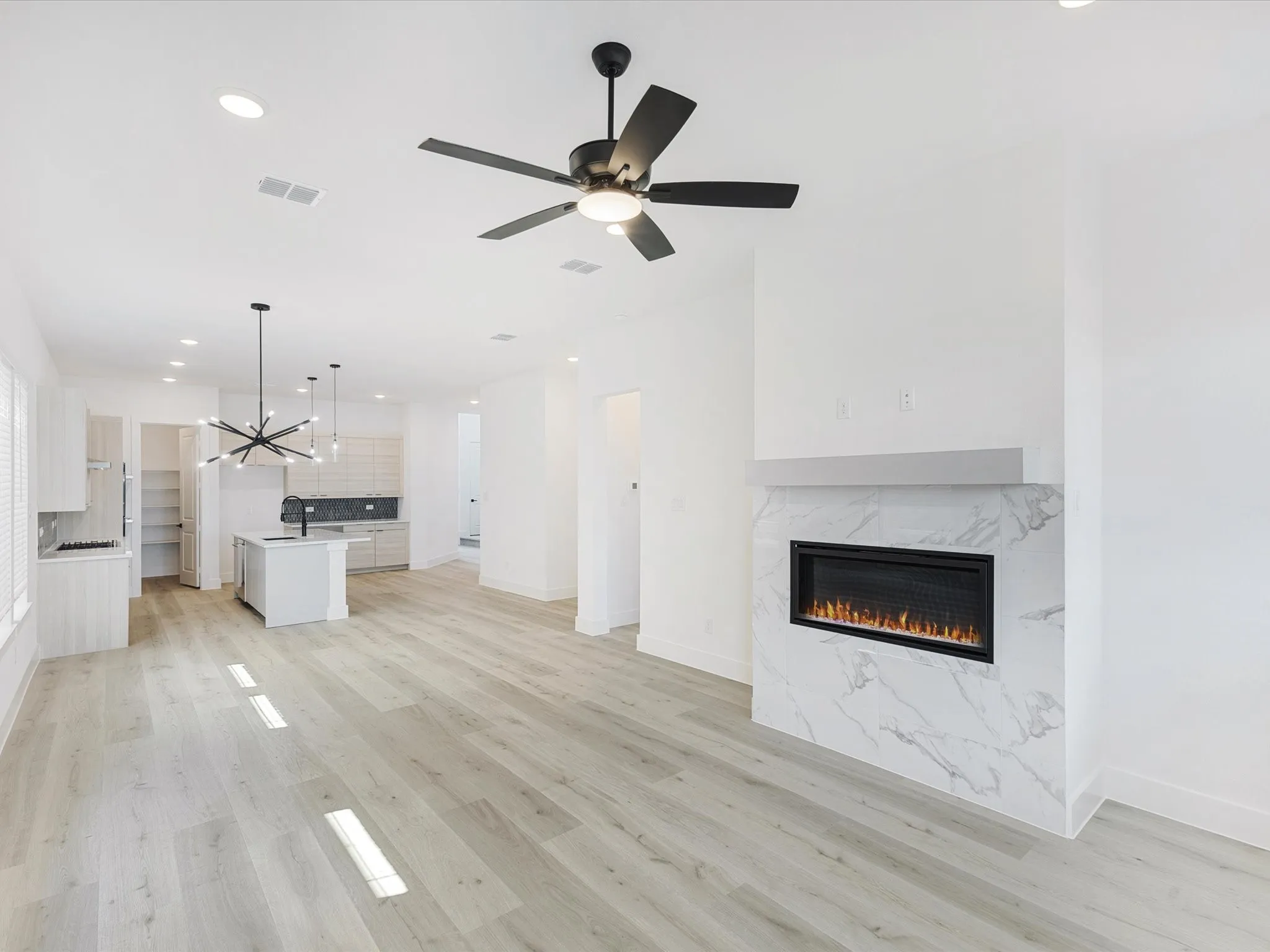 Unfurnished living room with recessed lighting, light wood-style flooring, a high end fireplace, a chandelier, and ceiling fan