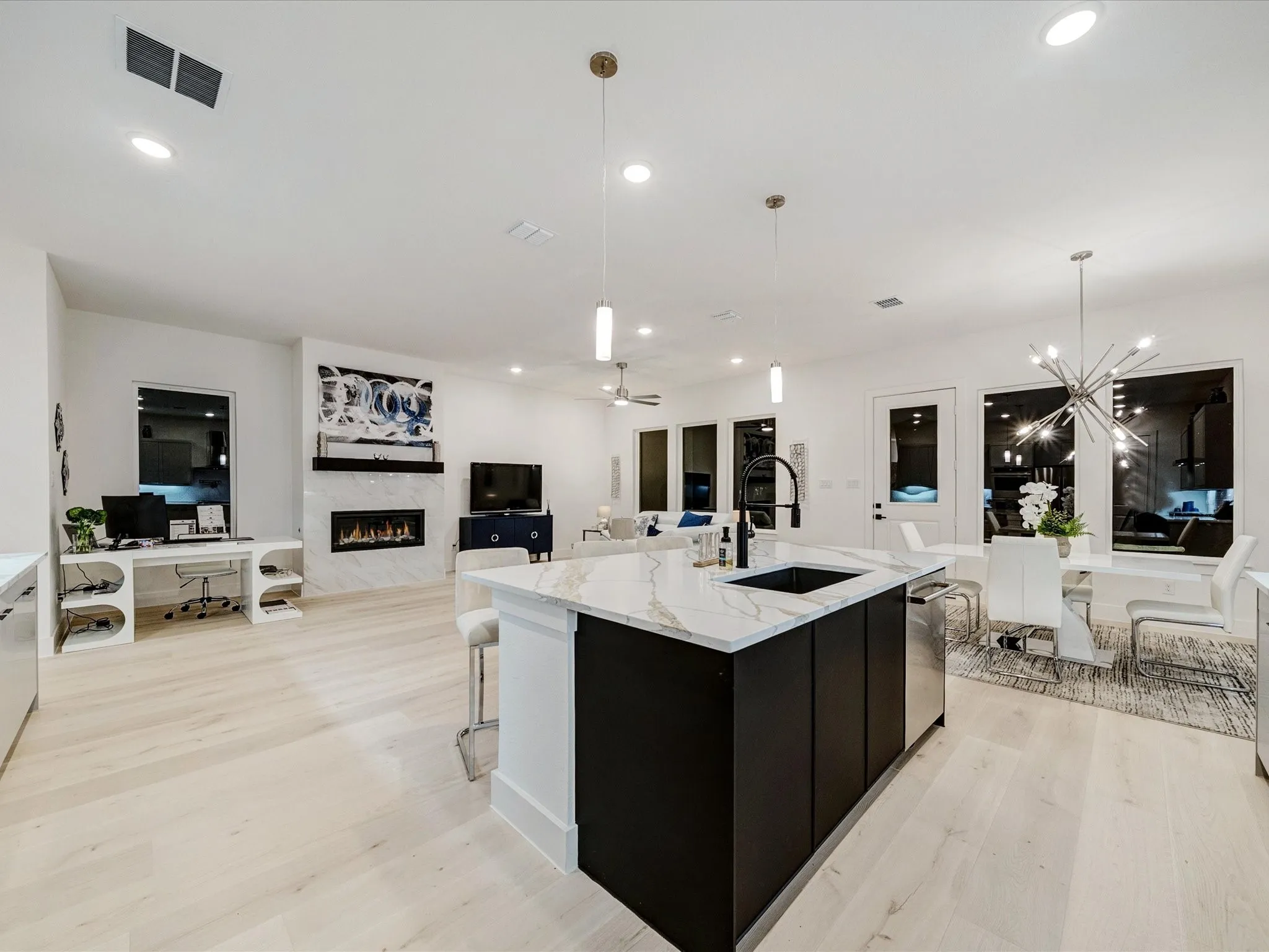 Kitchen featuring pendant lighting, light wood-type flooring, a premium fireplace, open floor plan, and ceiling fan