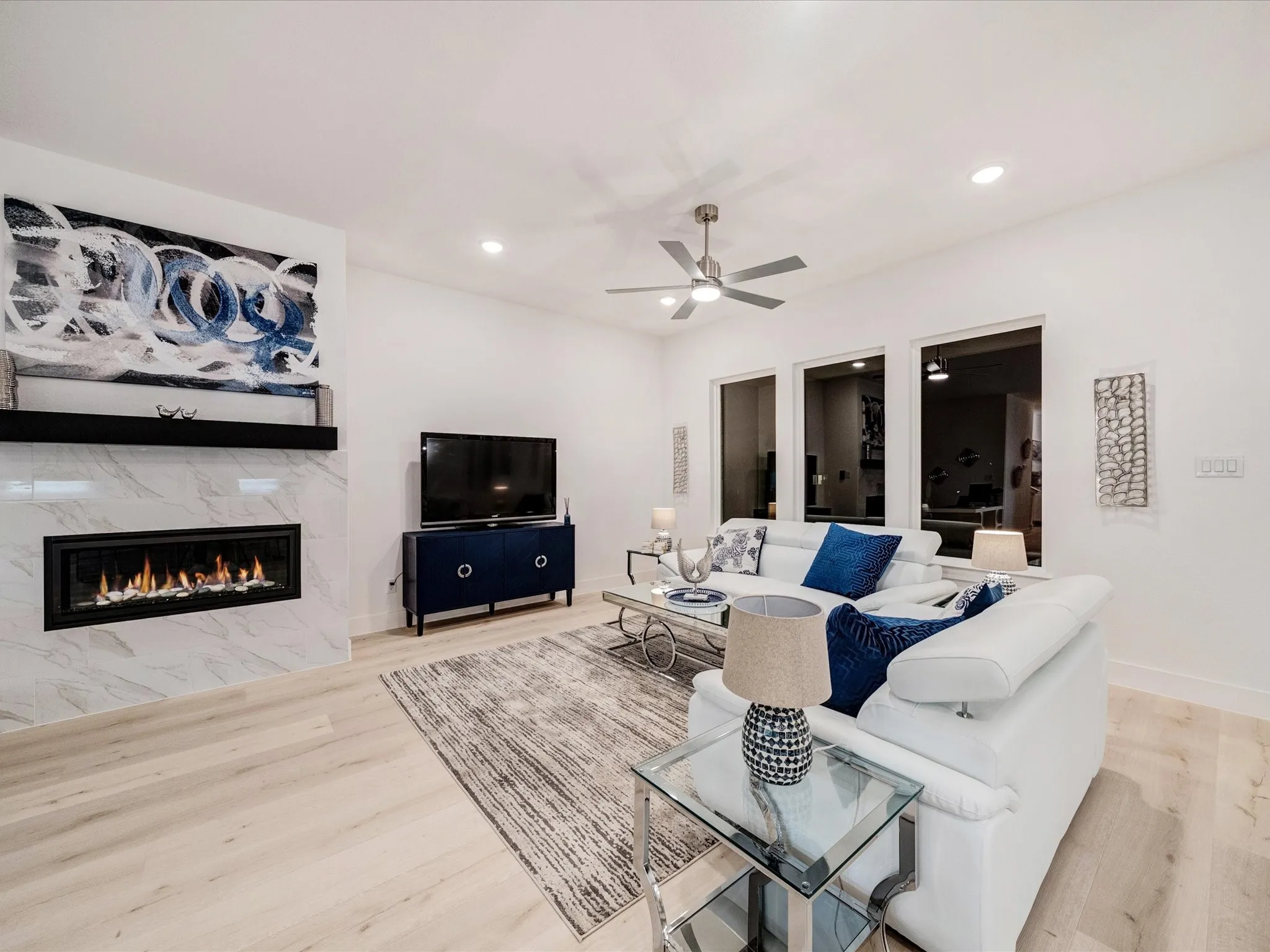 Living area with a high end fireplace, light wood-type flooring, recessed lighting, and a ceiling fan