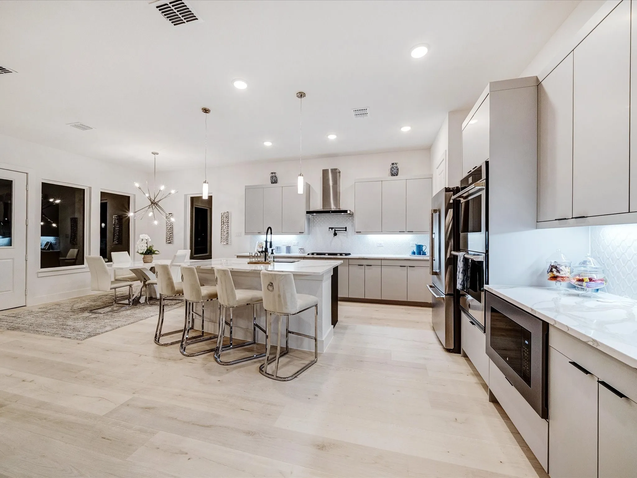 Kitchen with backsplash, modern cabinets, a breakfast bar, hanging light fixtures, and a chandelier