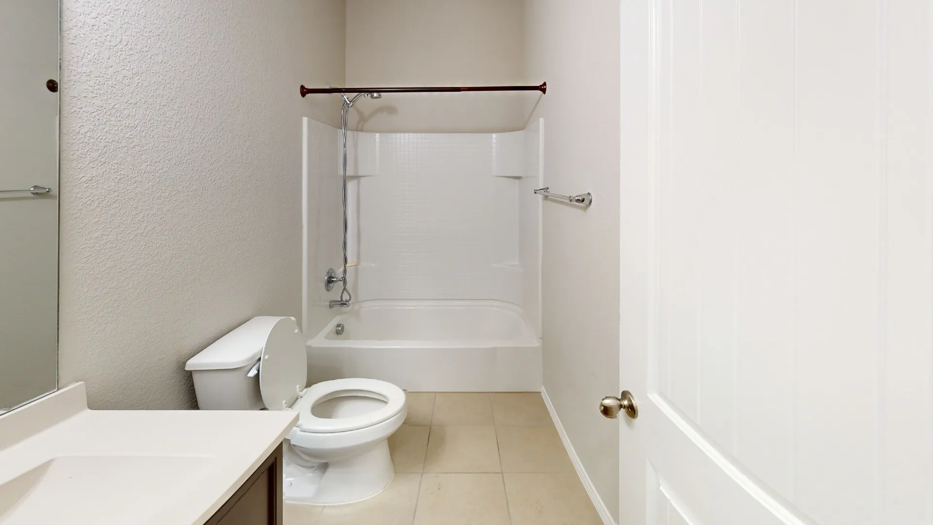 Bathroom featuring a white bathtub and shower combination, a toilet, a vanity with a light-colored countertop, and a white panel door