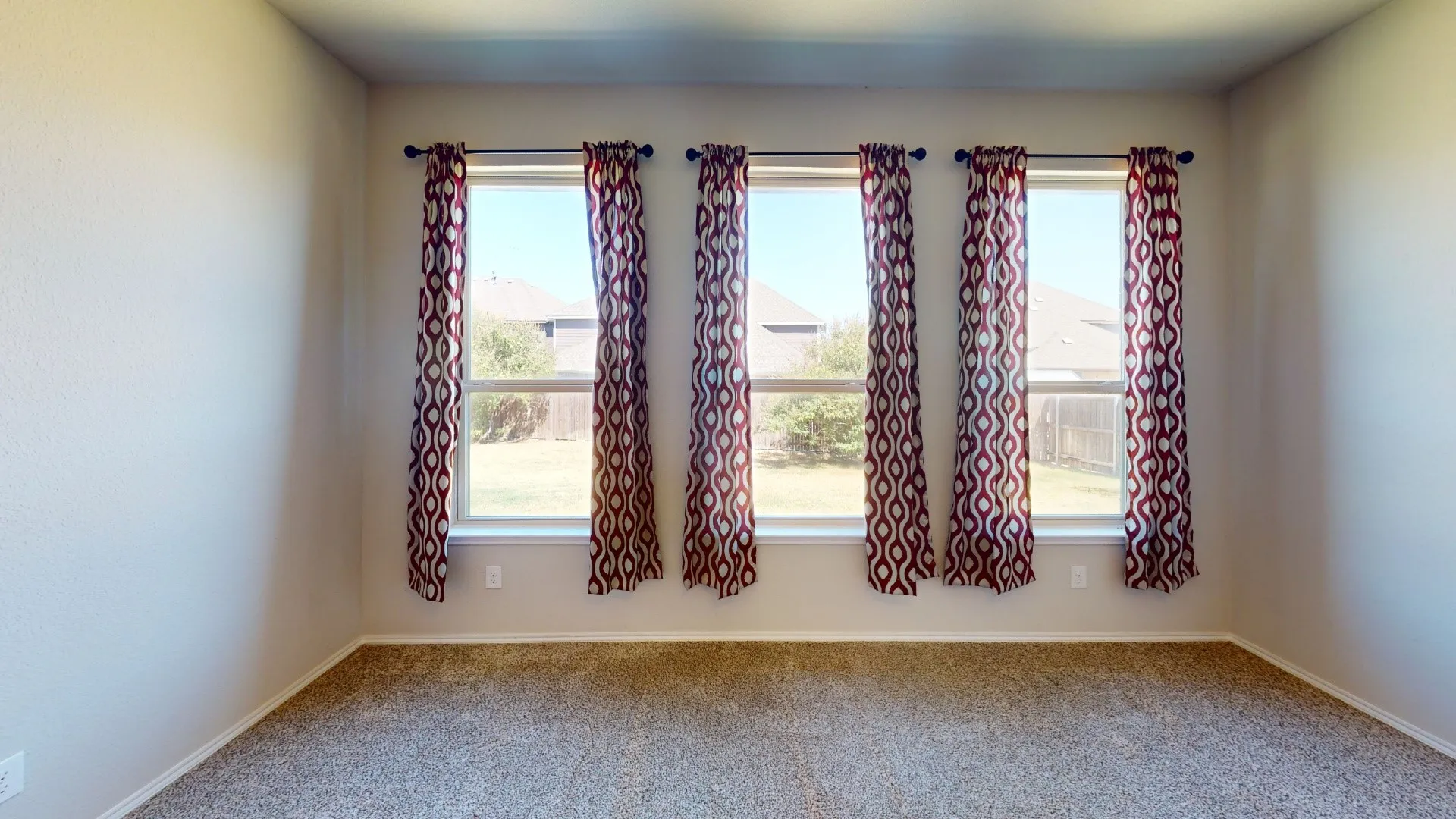 Four large windows, neutral wall color, and textured carpeting