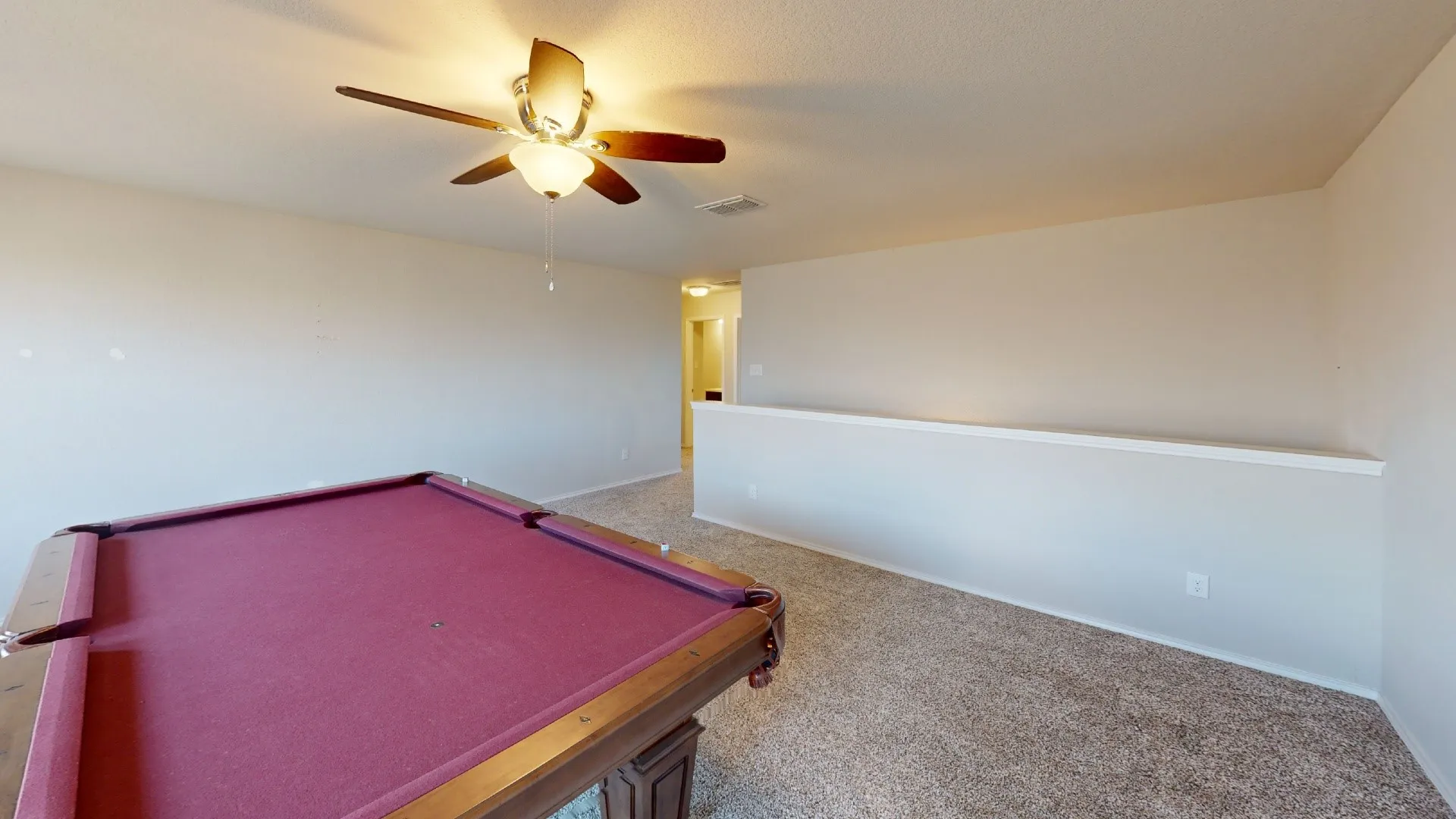 Carpeted room with a ceiling fan light fixture and a half-wall partition