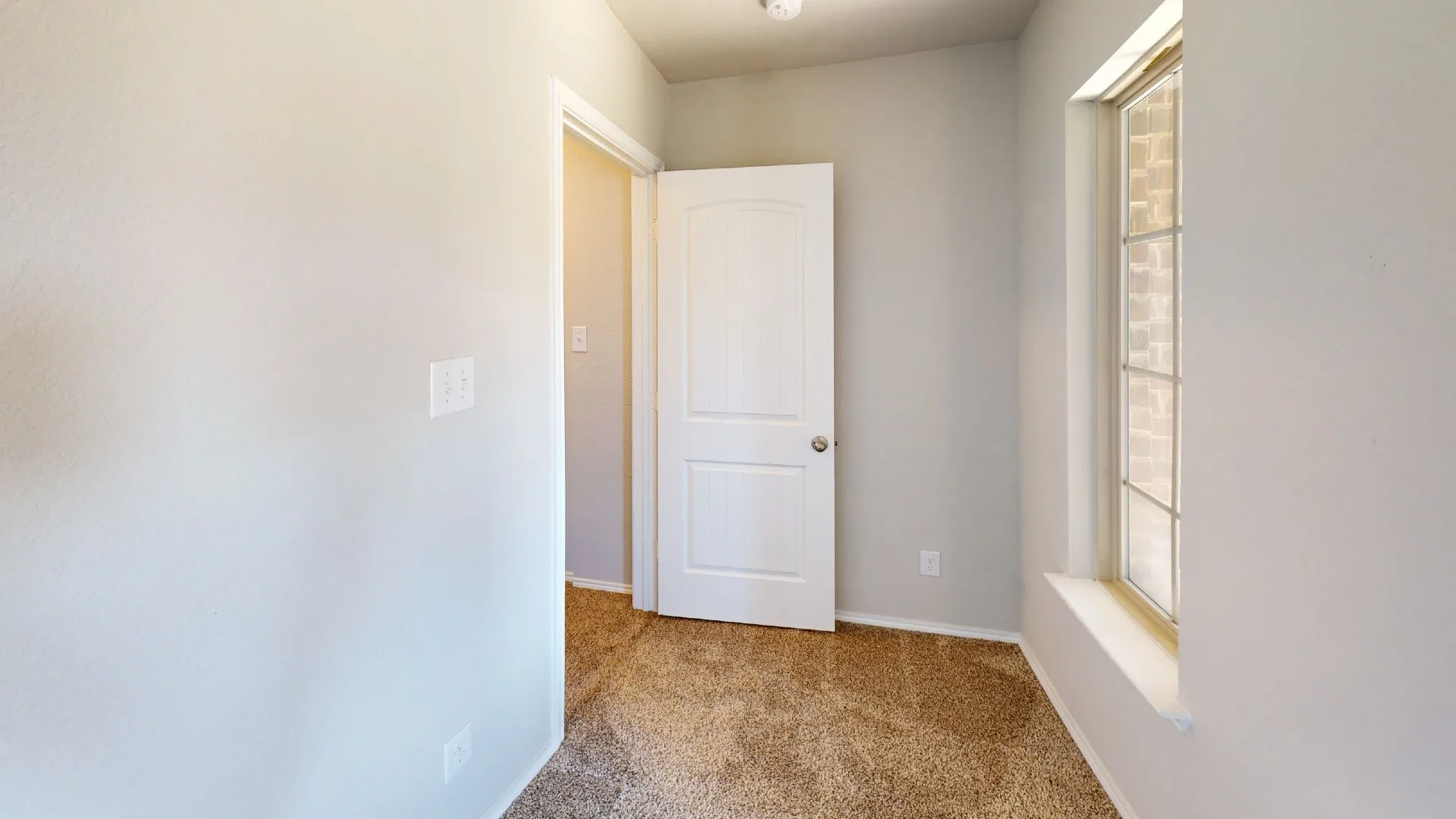 Carpeted flooring, neutral wall tones, interior door with a round knob, and a window with grid detailing