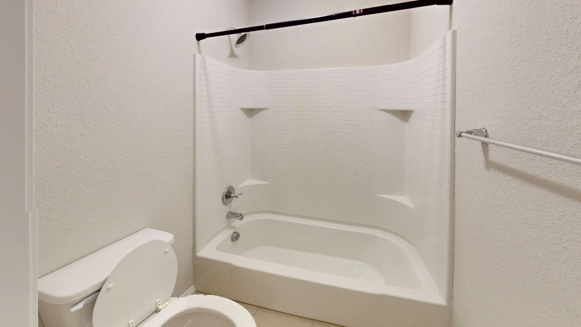 White bathtub and shower combination with chrome fixtures