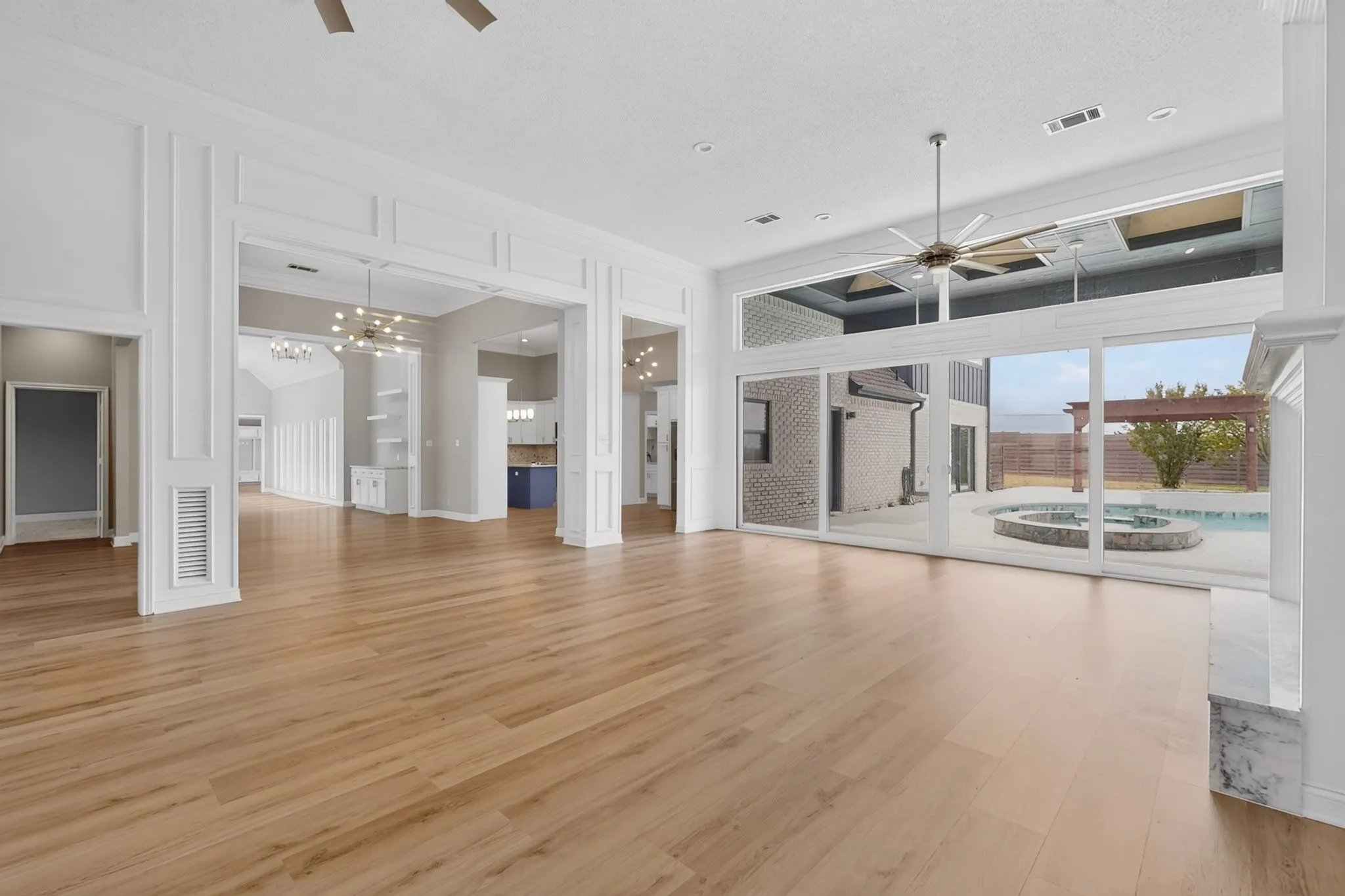 Spacious interior with wood-finish flooring, white trim, and a large ceiling fan