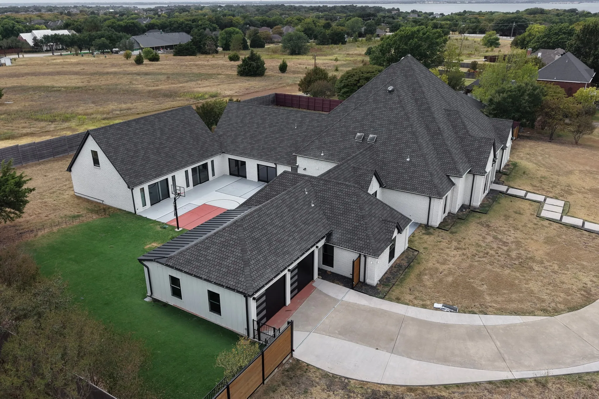 Single-story residence featuring a dark shingle roof, white exterior siding, and a concrete driveway