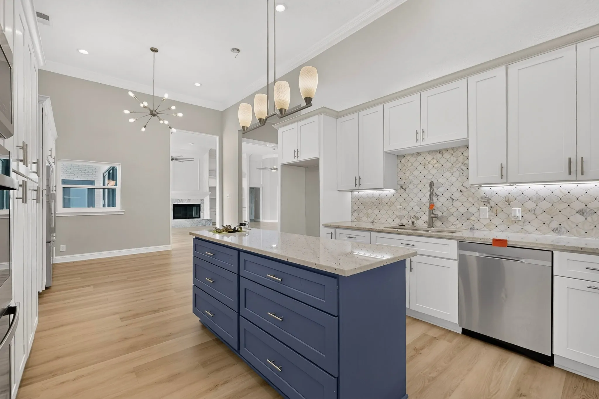 Kitchen featuring a blue island with a light-colored countertop, light wood-finish flooring, white cabinetry, and stainless steel appliances