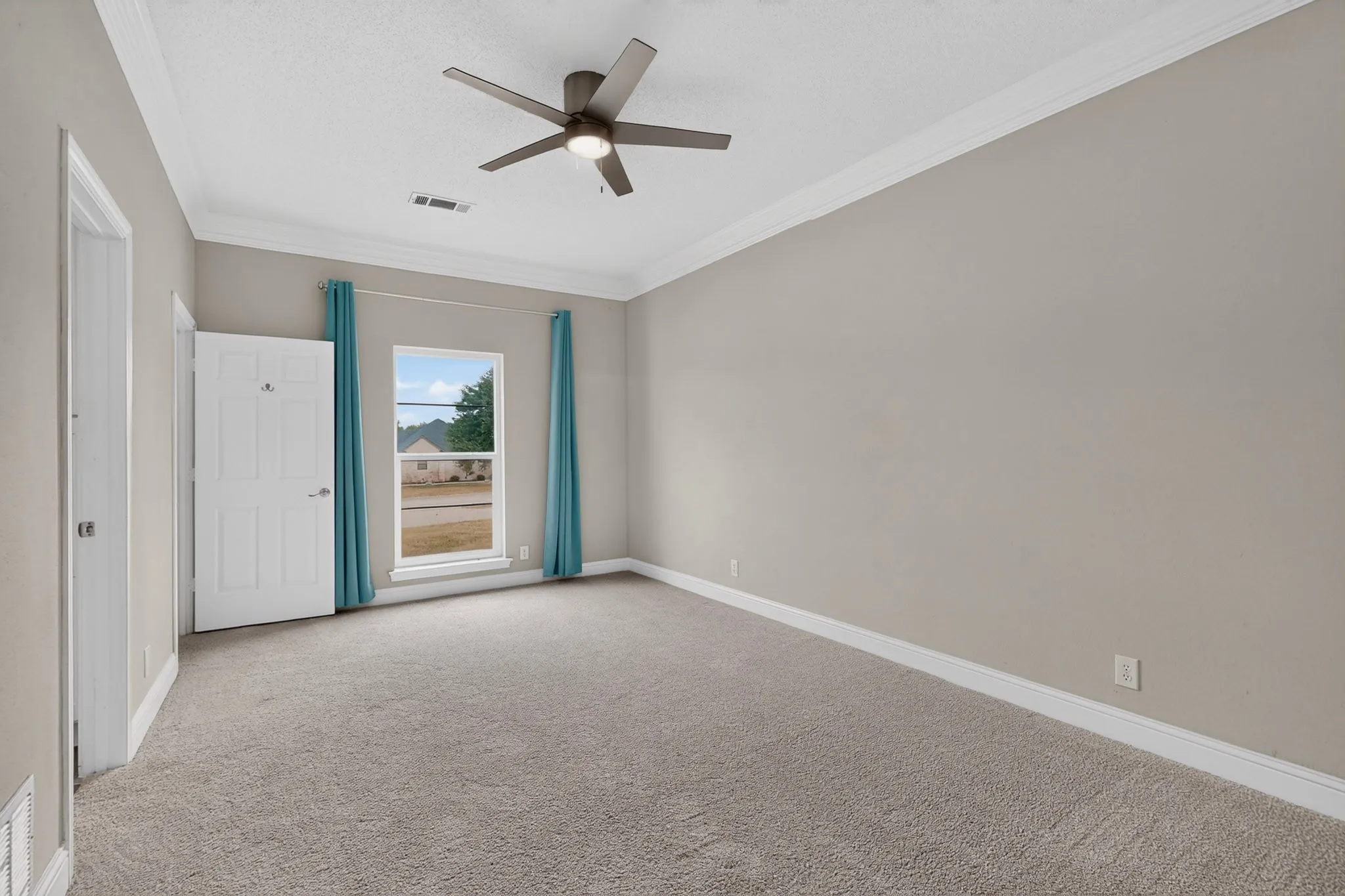 Spacious room featuring carpeting, a ceiling fan, a window, and crown molding