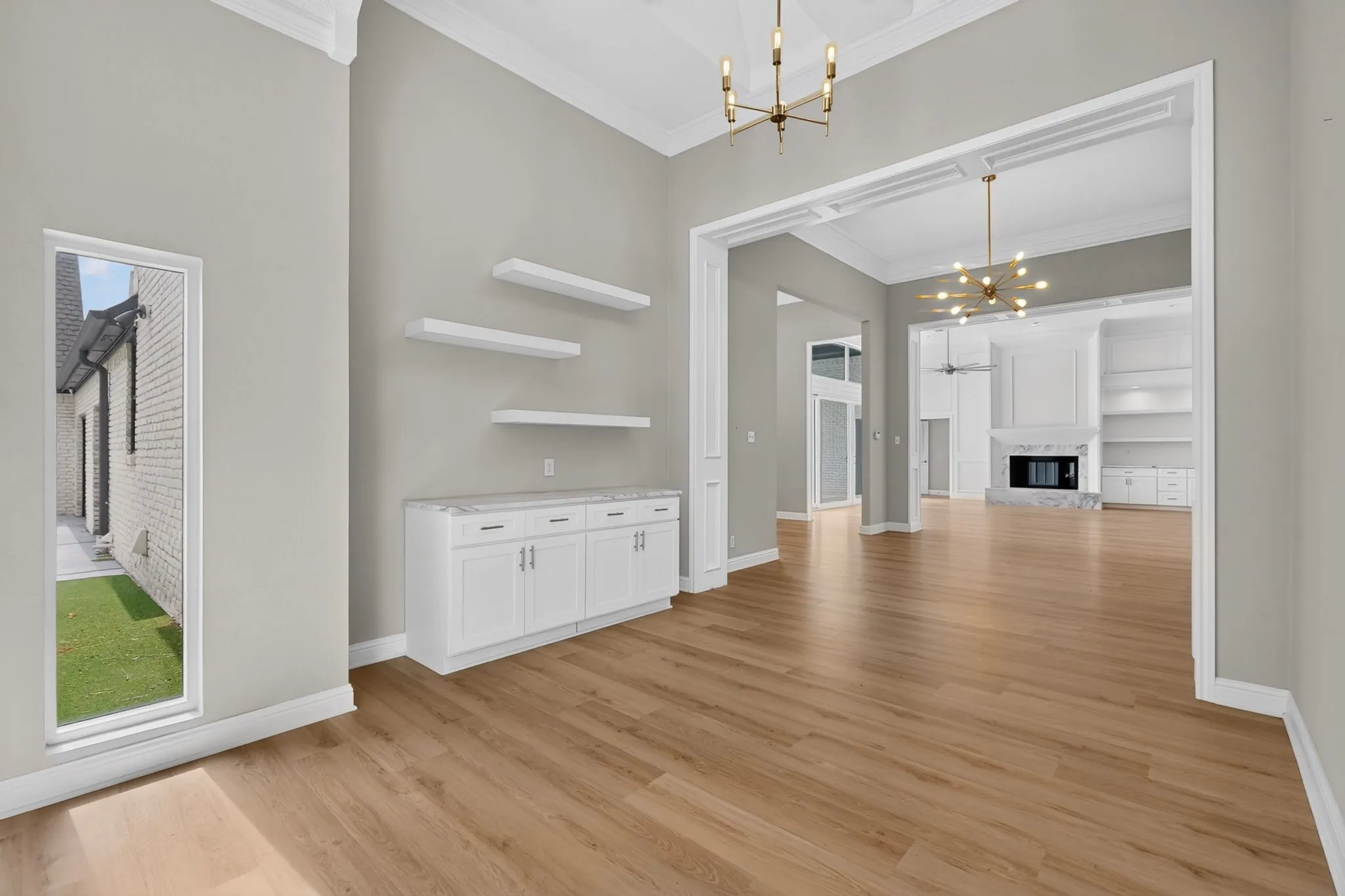 Wood-finish flooring throughout, crown molding, built-in cabinetry with a stone countertop, floating shelves, and an architectural archway