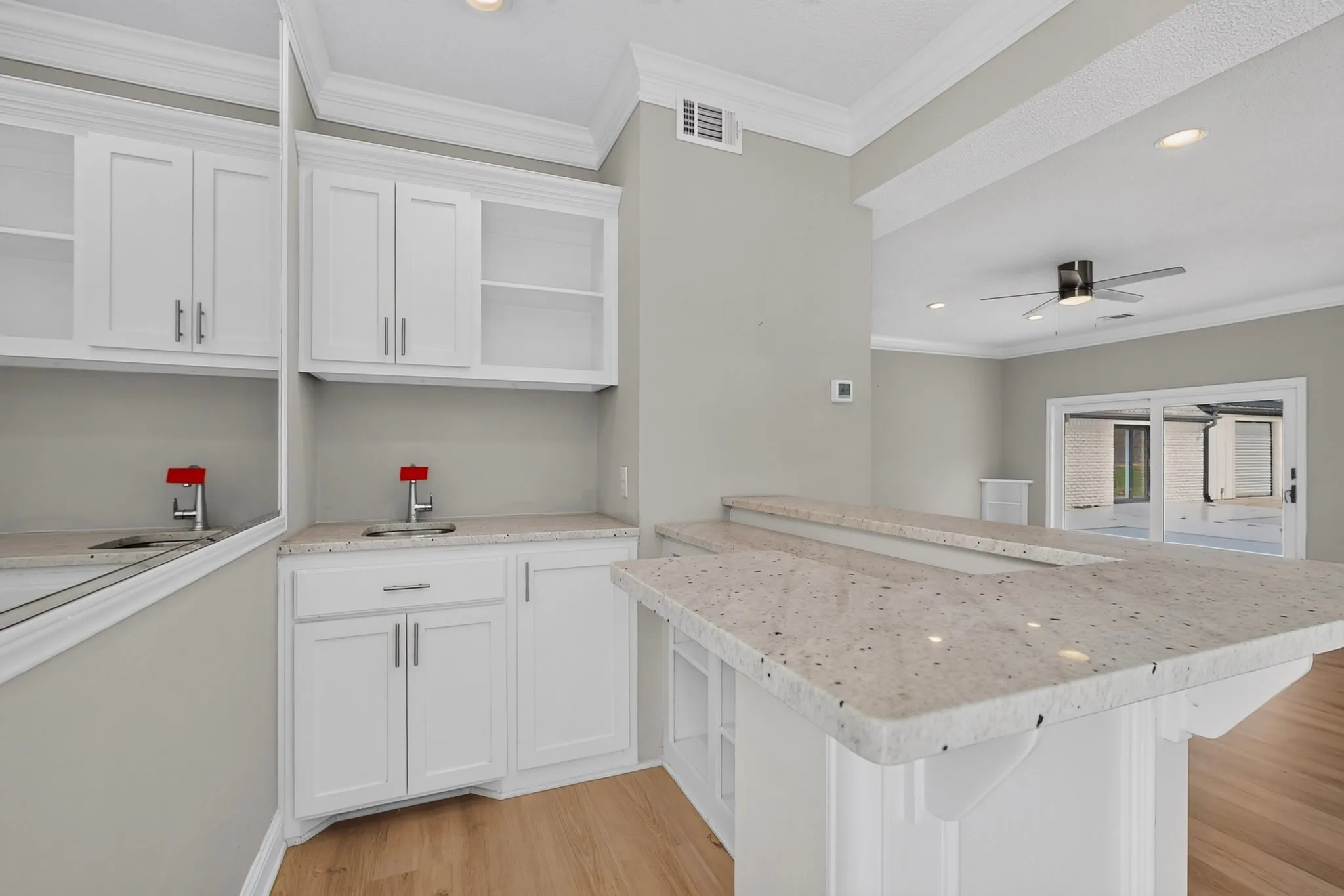 Built-in wet bar with white cabinetry, integrated sink, and light-toned countertop