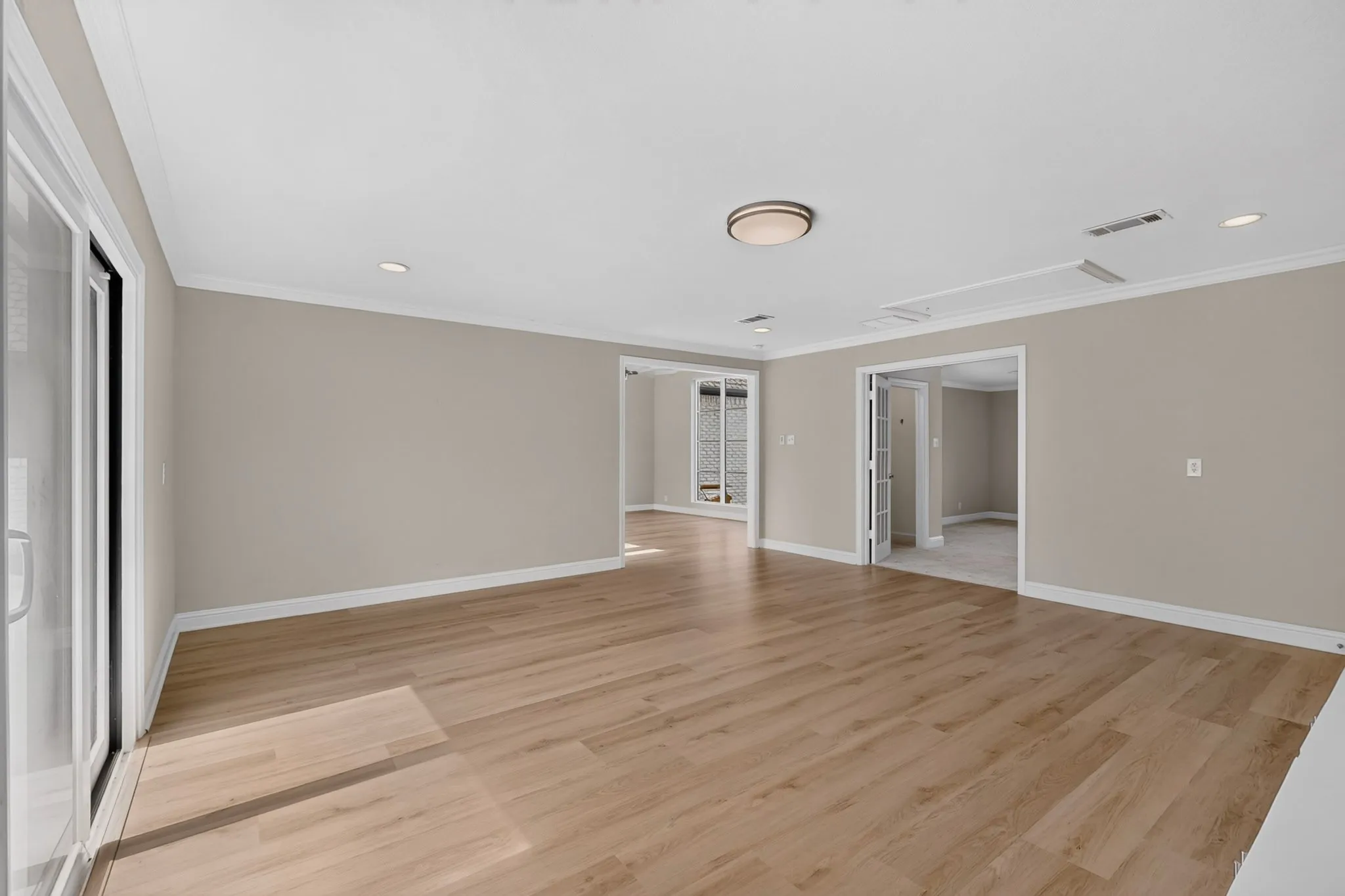 Wood-finish flooring, neutral wall tones, recessed lighting, crown molding, and sliding glass doors