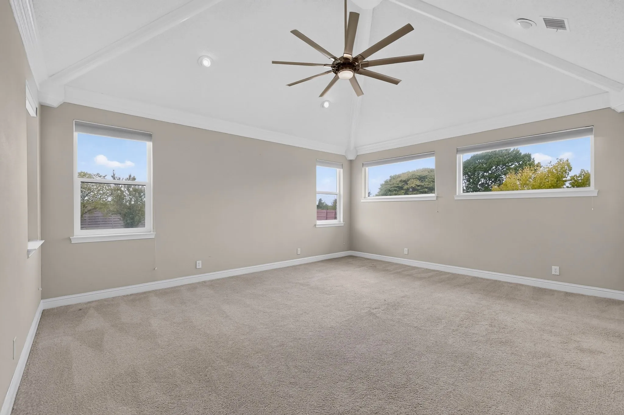Vaulted ceiling with exposed beams, ceiling fan, recessed lighting, multiple windows, and carpet flooring