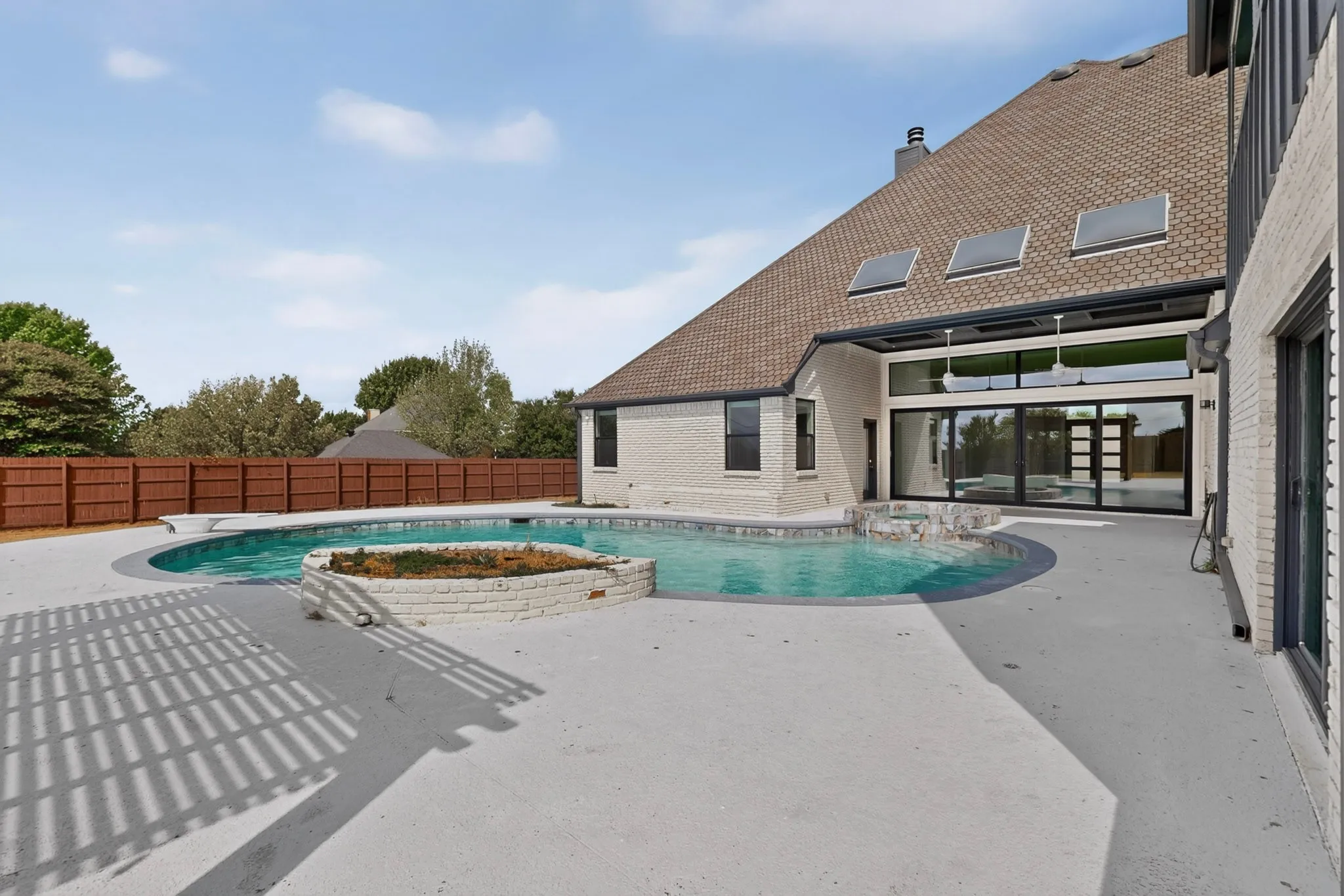 Expansive backyard featuring a curved swimming pool, a raised planter, and an attached spa