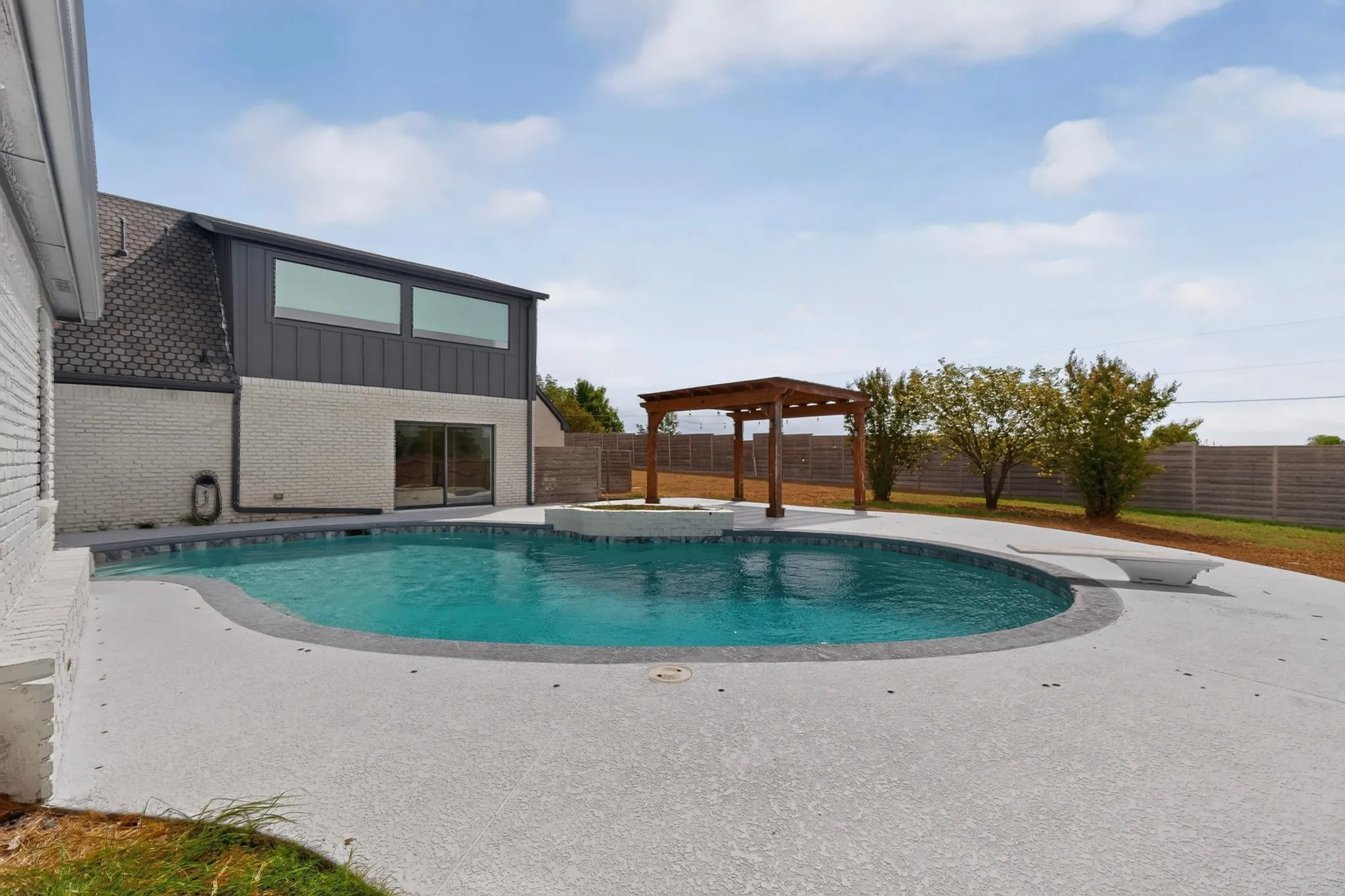 Curved swimming pool with integrated spa and concrete decking