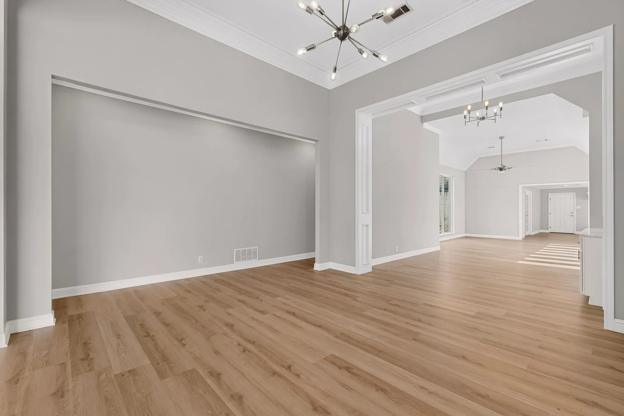 Wood-finish flooring throughout, complemented by crown molding and a contemporary sputnik chandelier