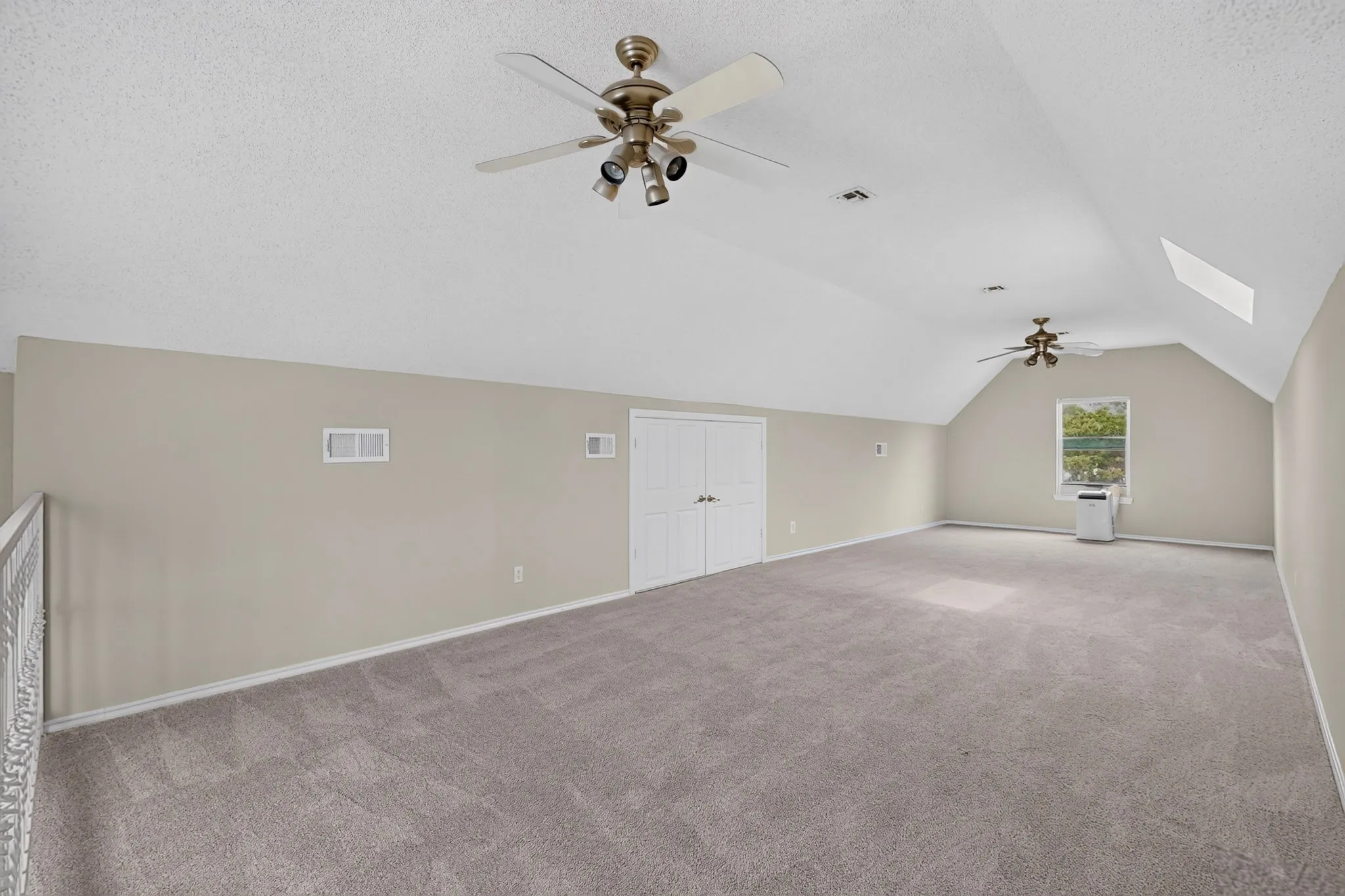 Vaulted ceiling, ceiling fans, integrated closet storage, window, and skylight