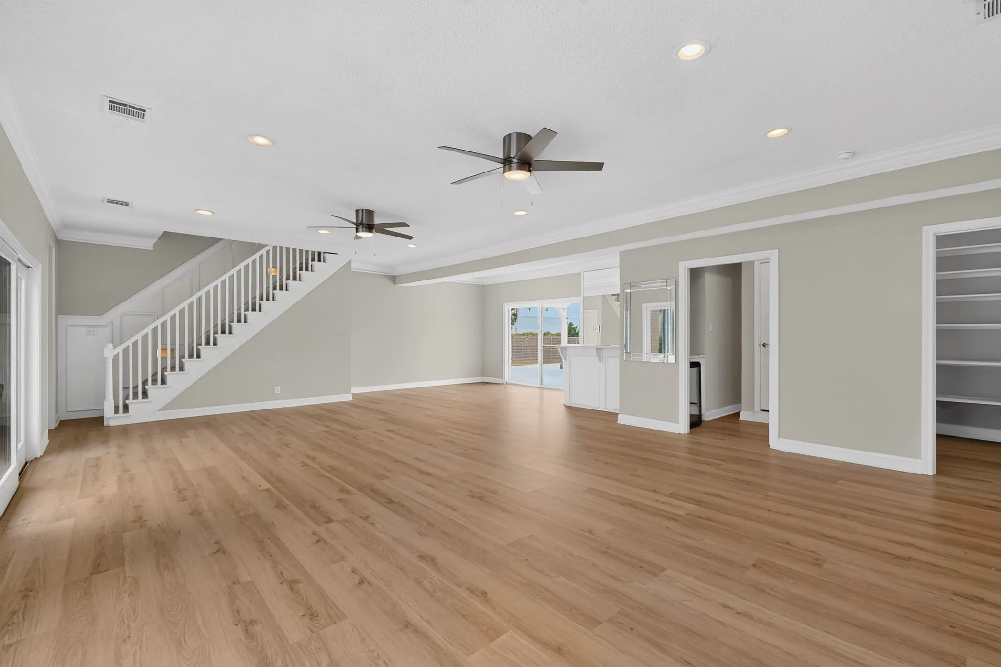 Spacious open-concept room featuring wood-finish flooring, recessed lighting, and crown molding