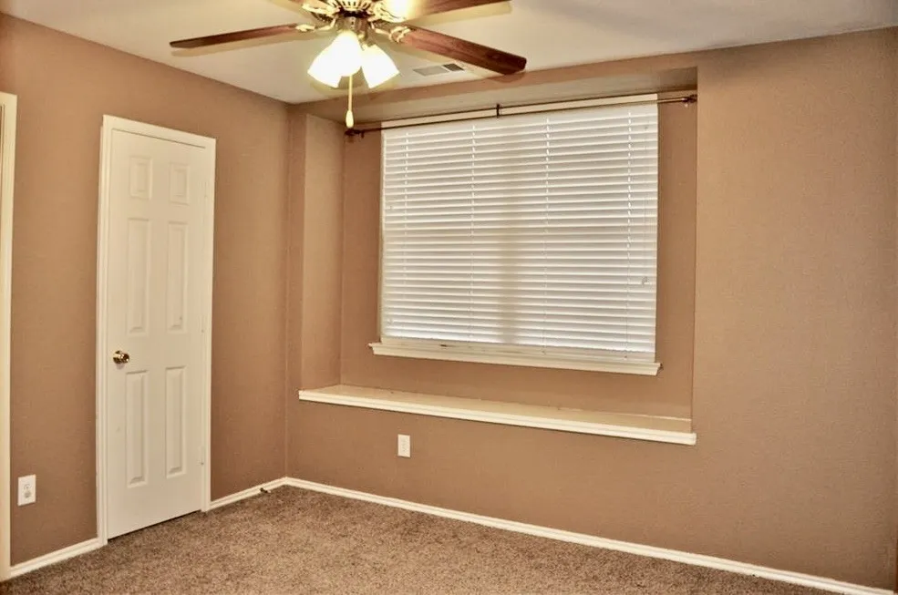 Bright secondary bedroom featuring plush carpeting, a ceiling fan, and a charming built-in window bench seat