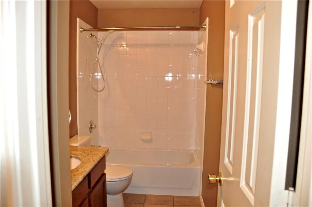 Hallway Bathroom with a tub/shower combination, white tile surround, vanity with a granite countertop