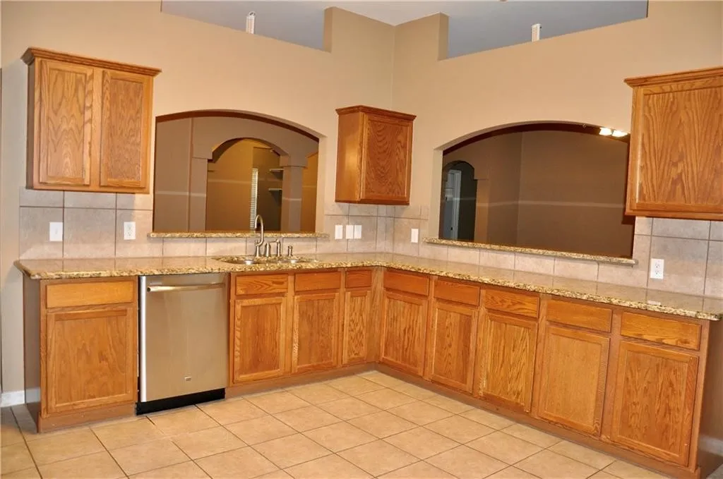Spacious kitchen layout with premium granite countertops, extensive cabinetry, and durable tile flooring