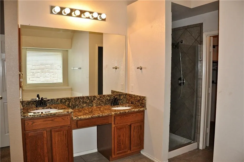 Luxurious primary bath boasting a double vanity with granite countertops and a built-in makeup vanity desk
