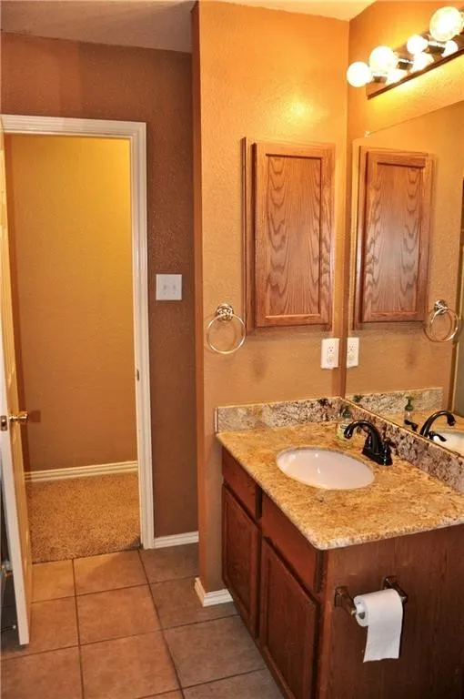 Hallway Bathroom features vanity with a granite countertop, undermount sink, and wood-finish cabinetry