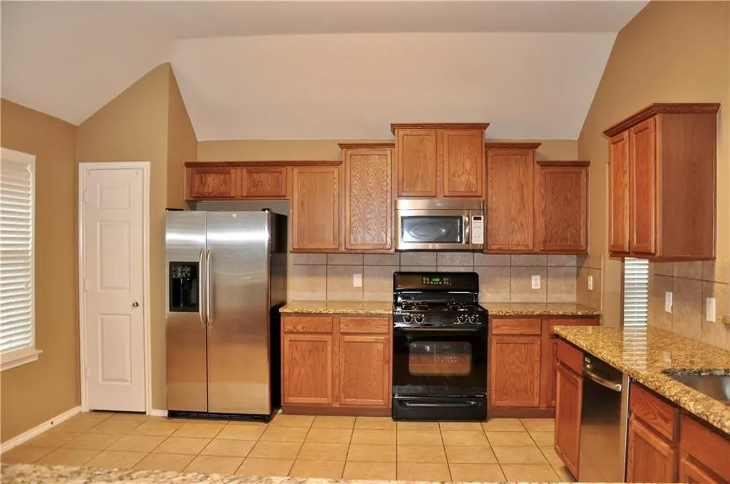 Modern kitchen setup equipped with a built-in microwave, gas range, dishwasher, and a stainless steel refrigerator