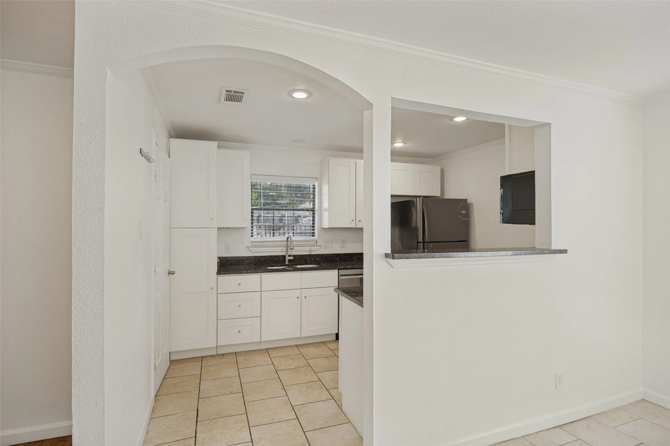 Kitchen featuring white cabinetry, dark stone countertops, stainless steel appliances, and tile flooring