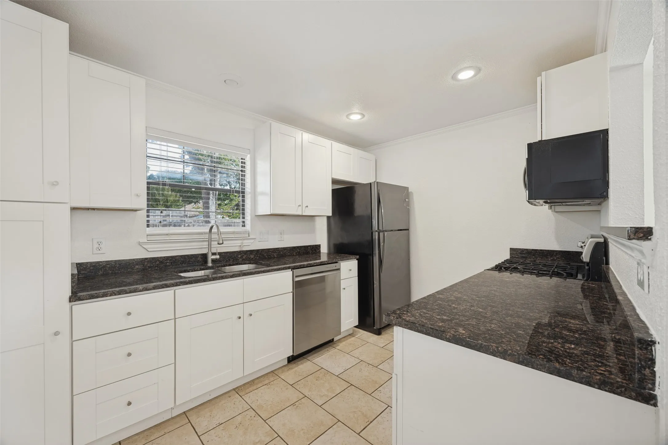 Kitchen featuring white cabinetry, dark stone countertops, stainless steel appliances, recessed lighting, and tile flooring