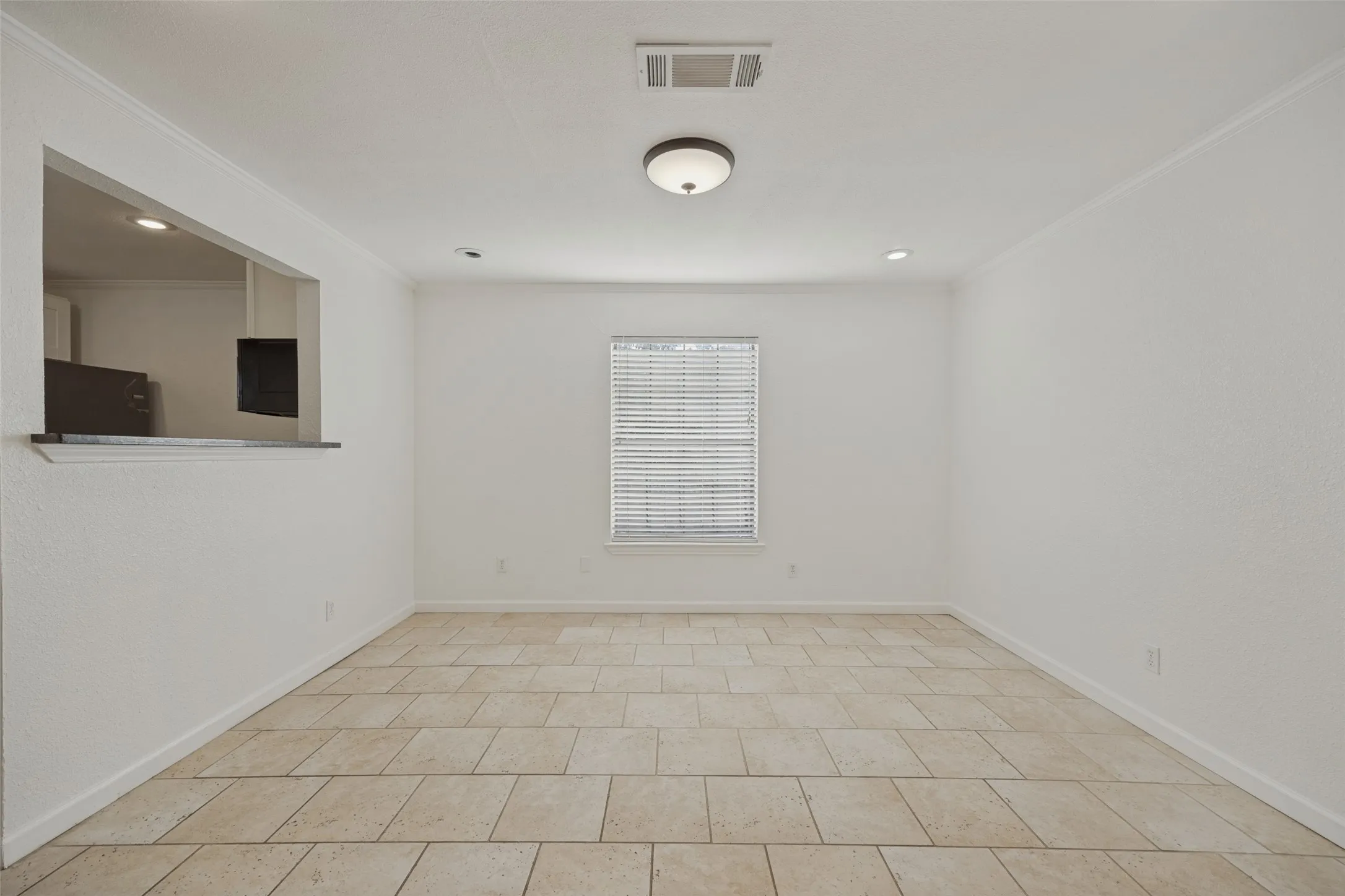 Light-toned tile flooring, recessed lighting, and a pass-through window with a countertop