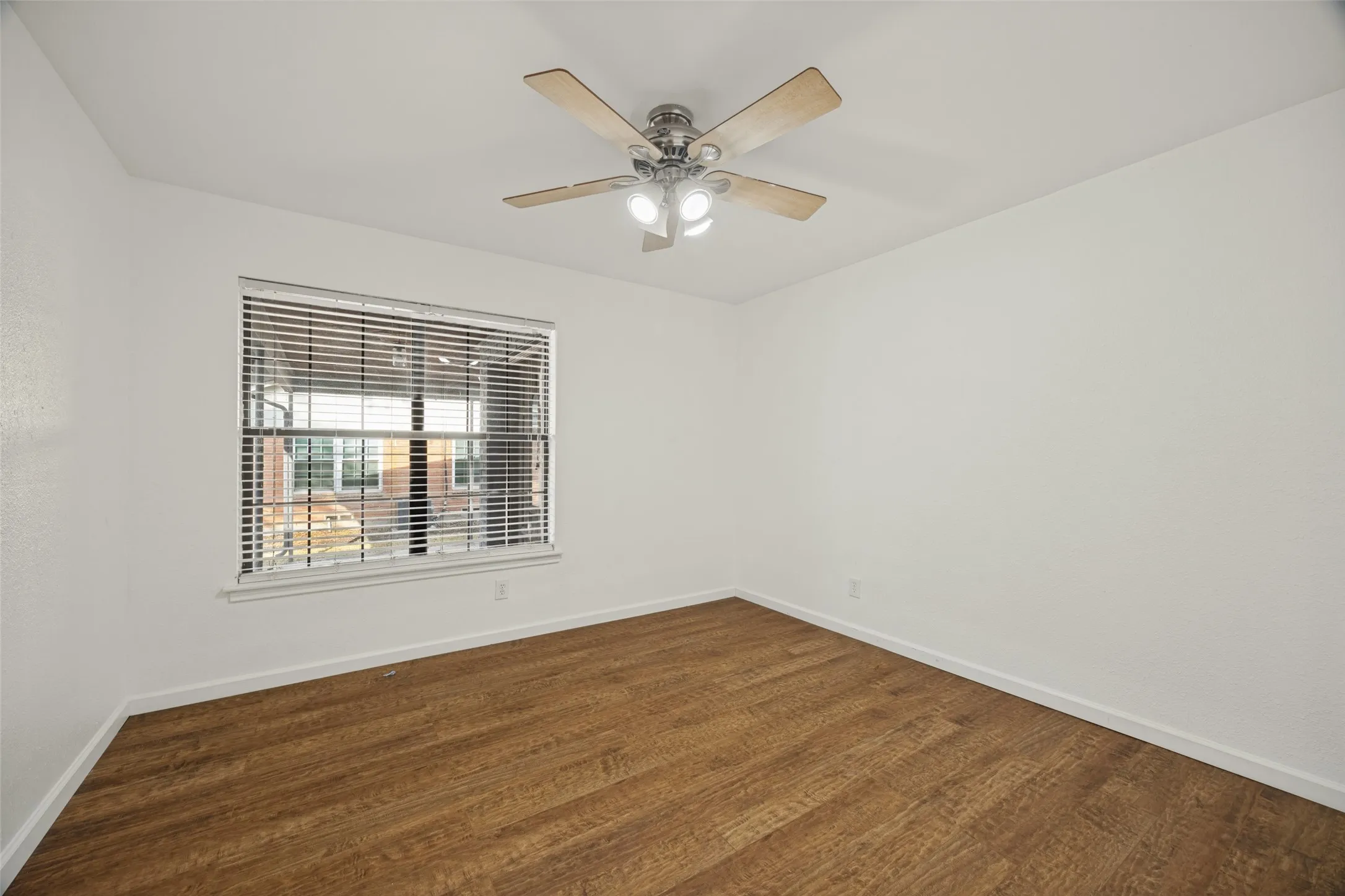 Wood-finish flooring, white walls, and a window with horizontal blinds
