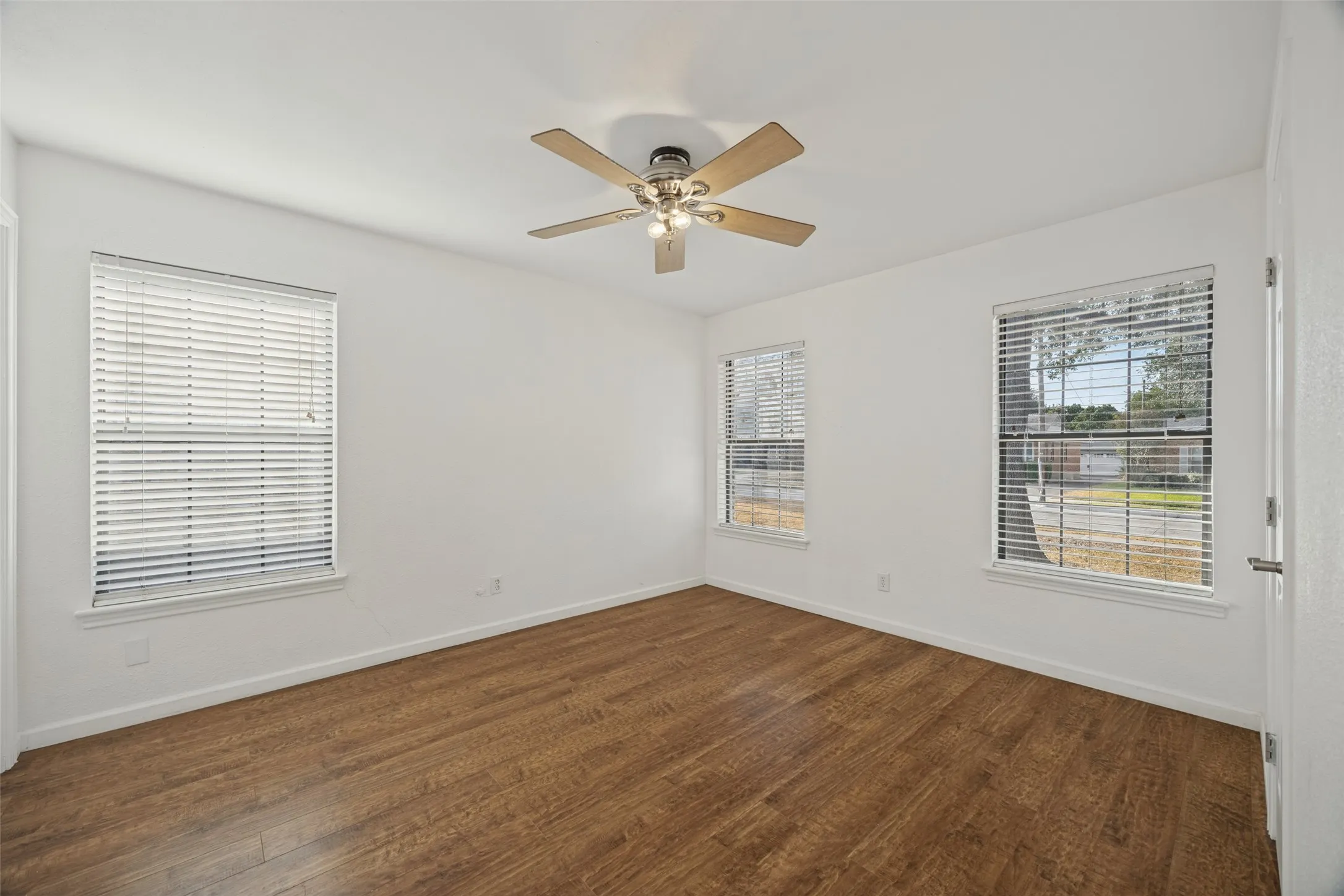 Wood-finish flooring, white walls, and a ceiling fan with light fixture