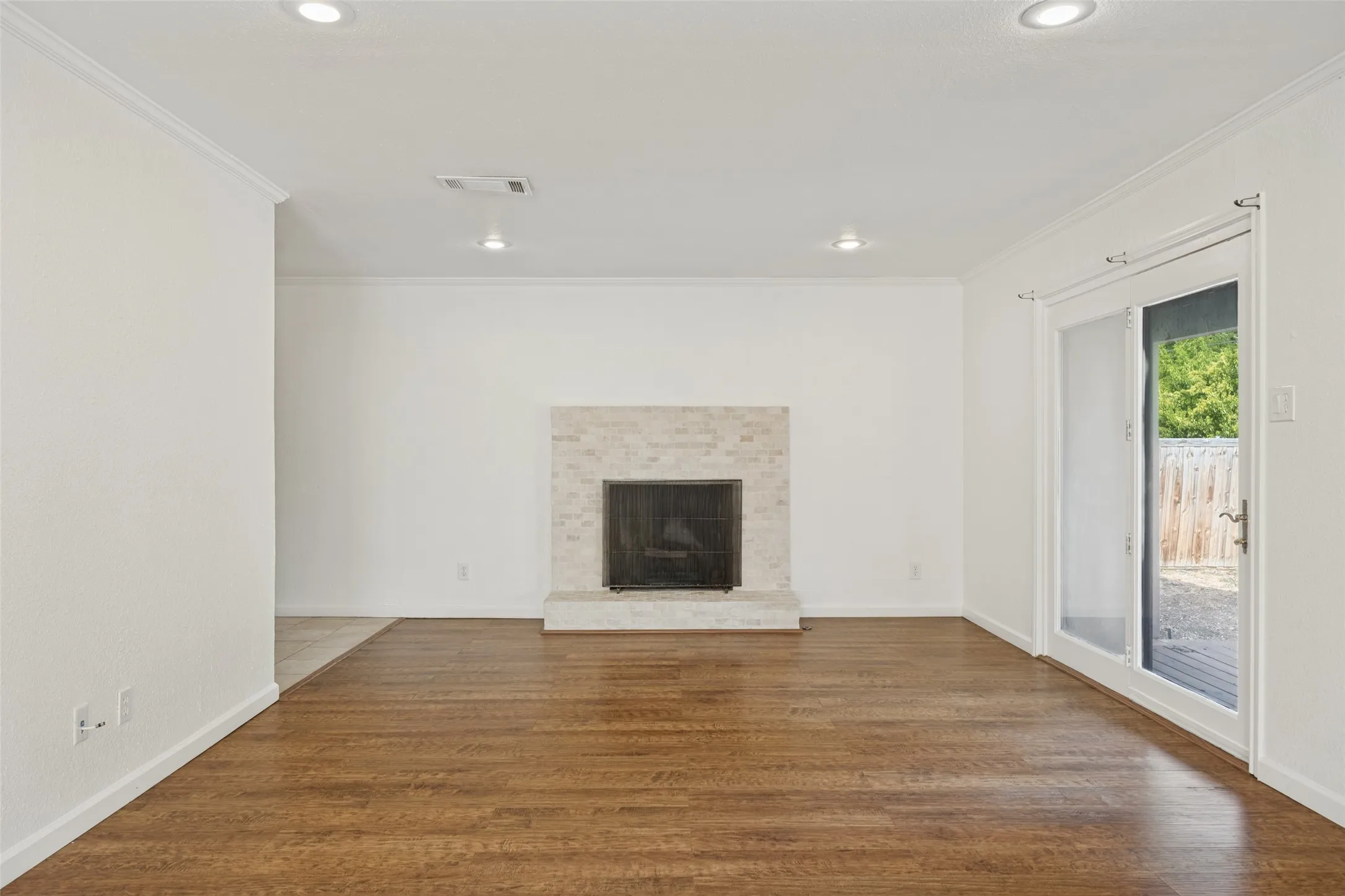 Hardwood flooring, recessed lighting, brick-clad fireplace, and sliding glass door