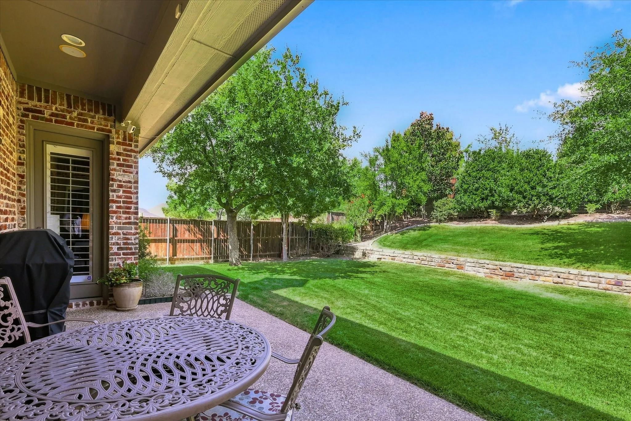 Covered patio with recessed lighting, brick exterior, and a privacy fence