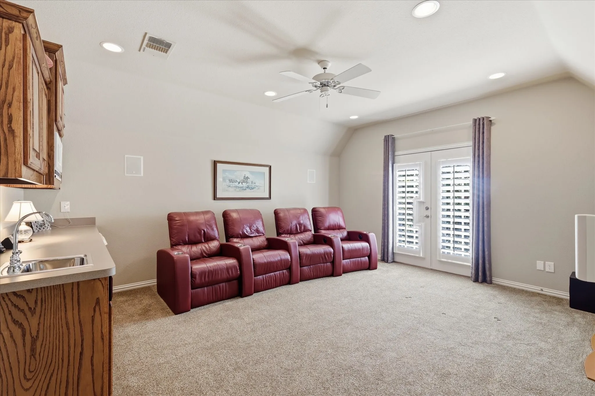 Recessed lighting, wood-finish cabinetry, built-in sink, double doors with interior shutters, and a ceiling fan