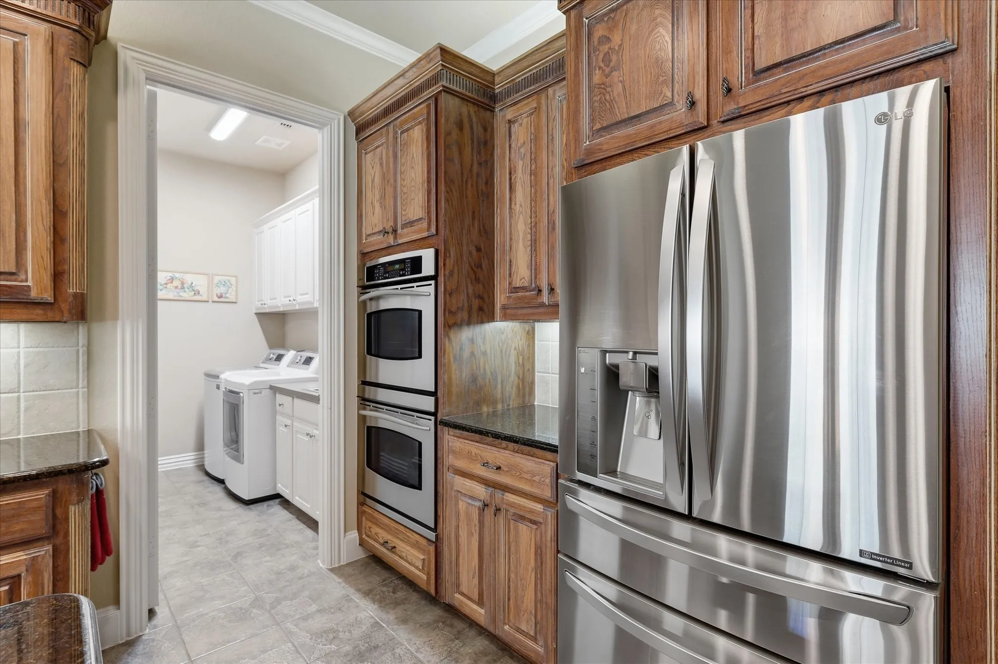 Wood cabinetry with crown molding, stainless steel double ovens, and a stainless steel refrigerator