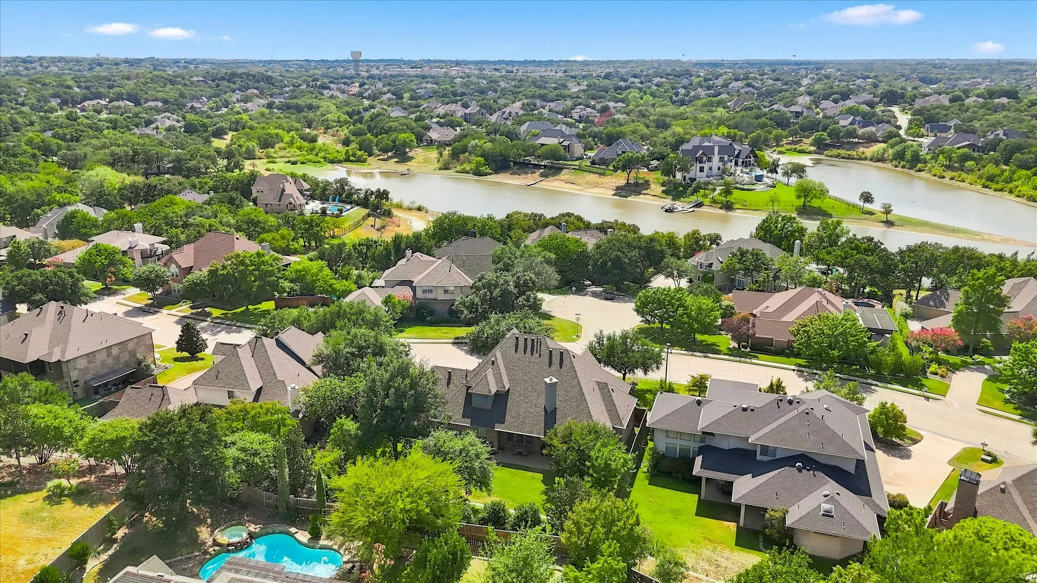 Expansive residential area with mature trees and a prominent body of water