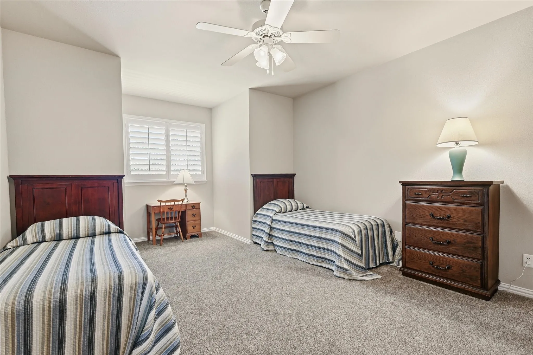 Carpeted flooring, white ceiling fan with light, and window with plantation shutters