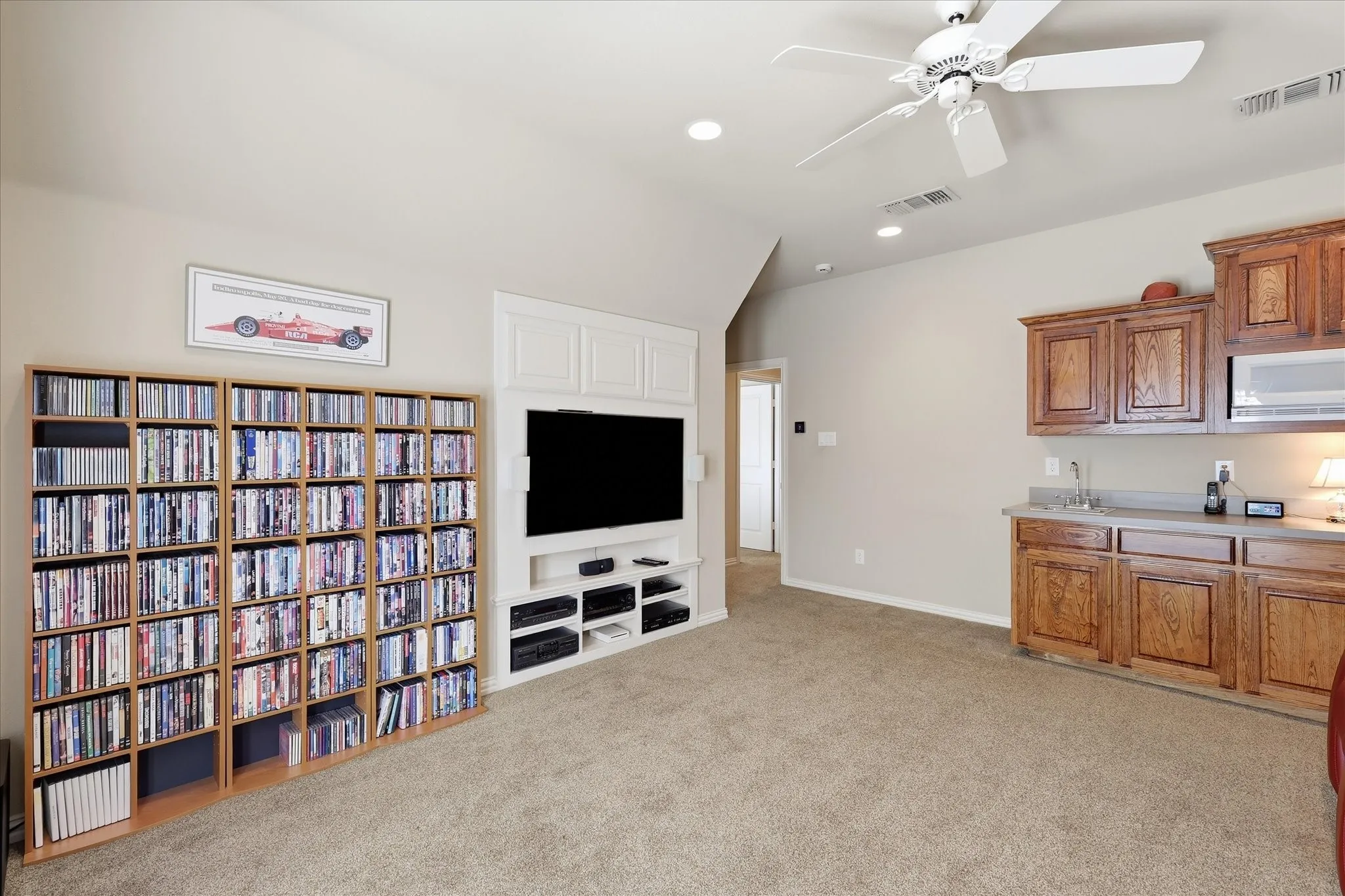 Built-in media center, recessed lighting, ceiling fan, and wet bar with wood cabinetry and countertop