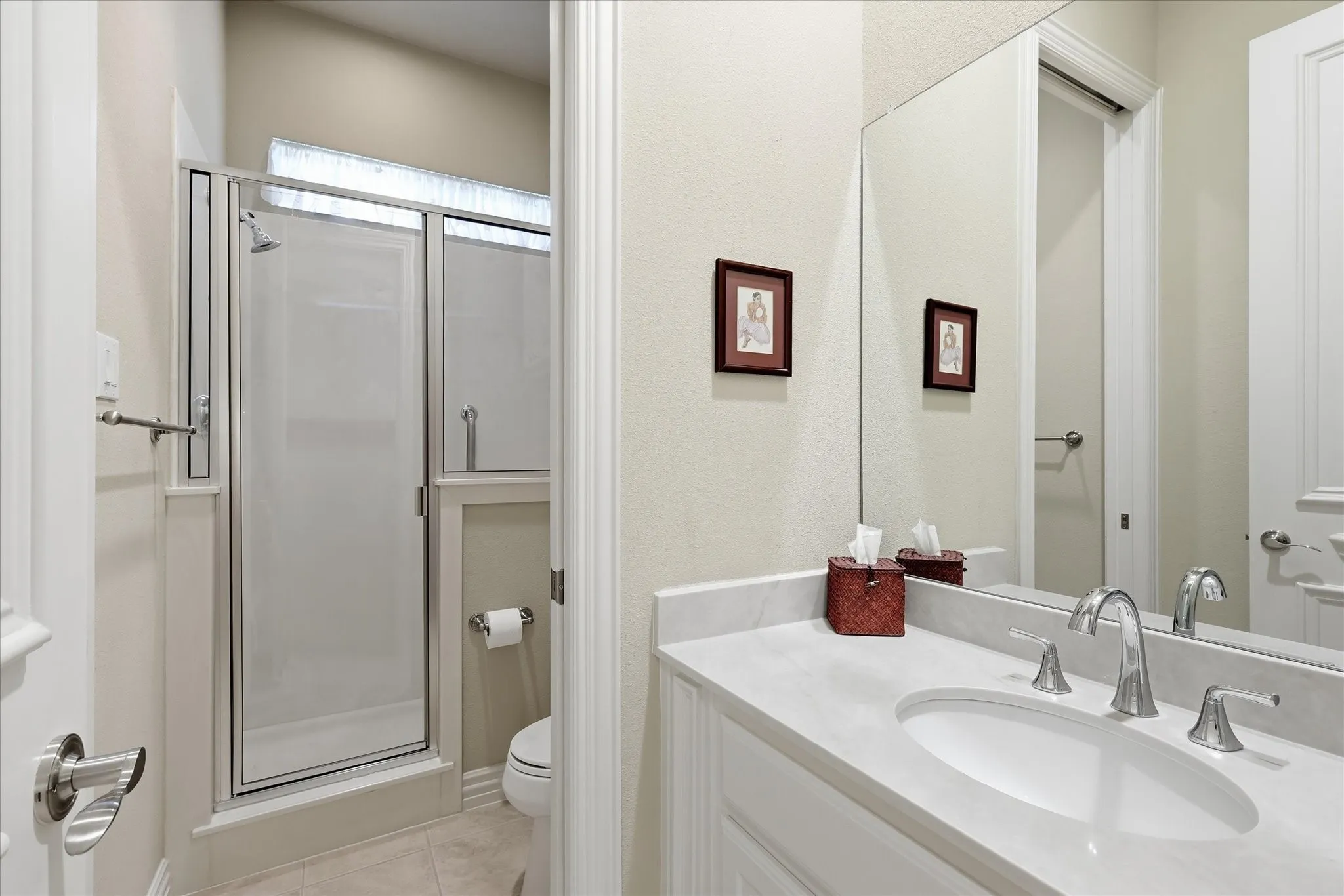 Shower enclosure with a glass door, vanity with an integrated sink, polished chrome faucet, and full-width mirror