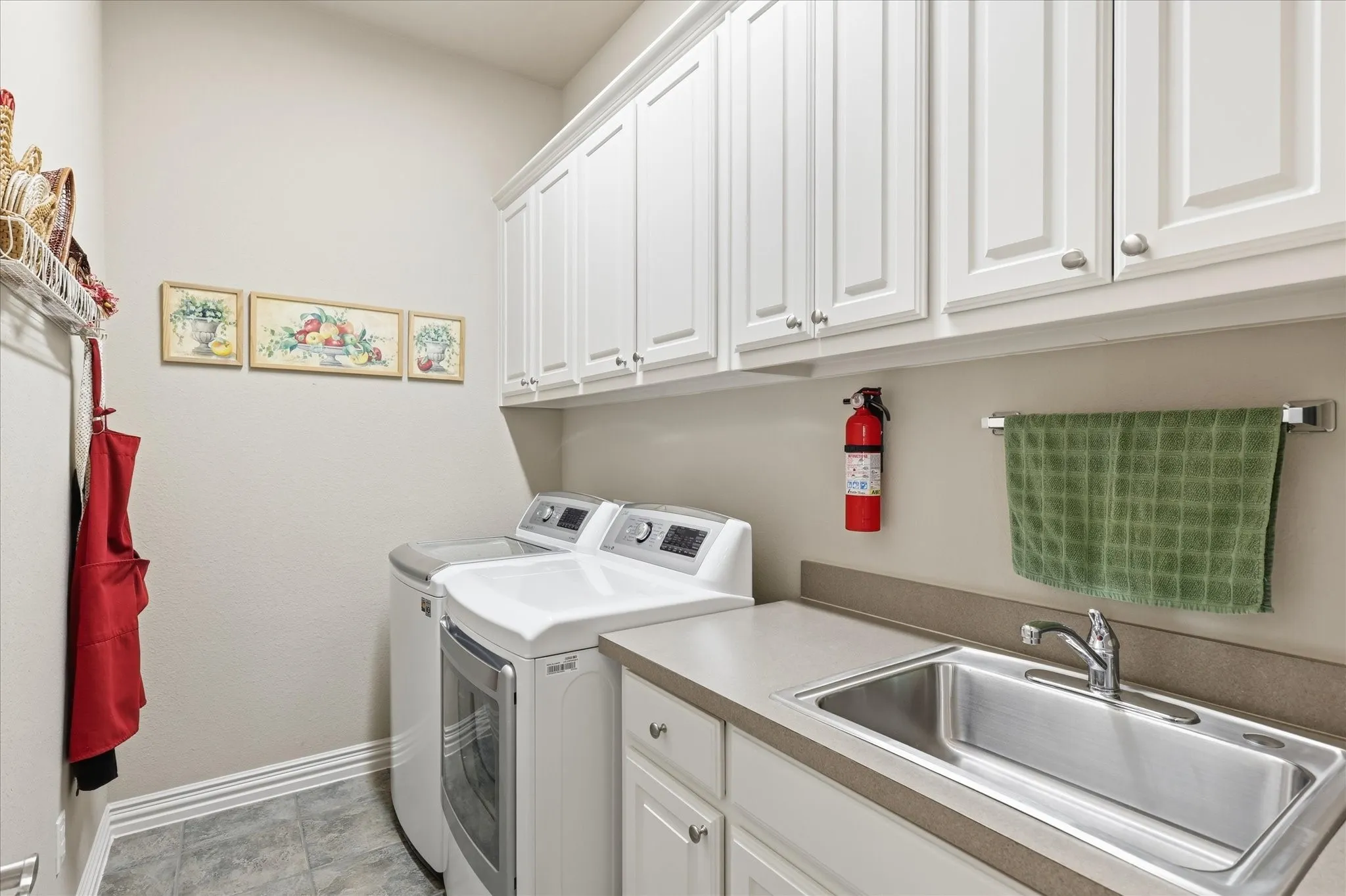 White upper cabinetry, built-in sink with a countertop, tile flooring, and a wall-mounted towel bar