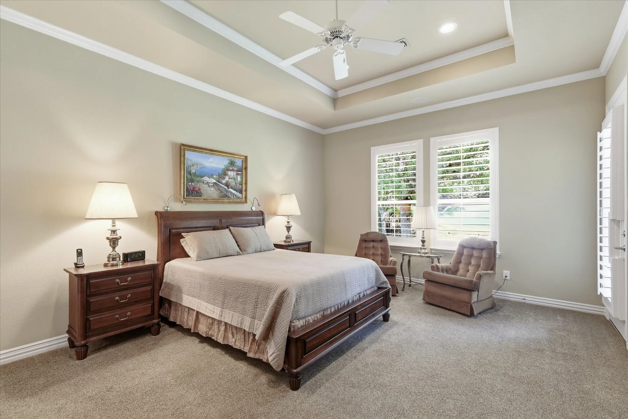 Tray ceiling with crown molding, ceiling fan, recessed lighting, carpet flooring, and white plantation shutters