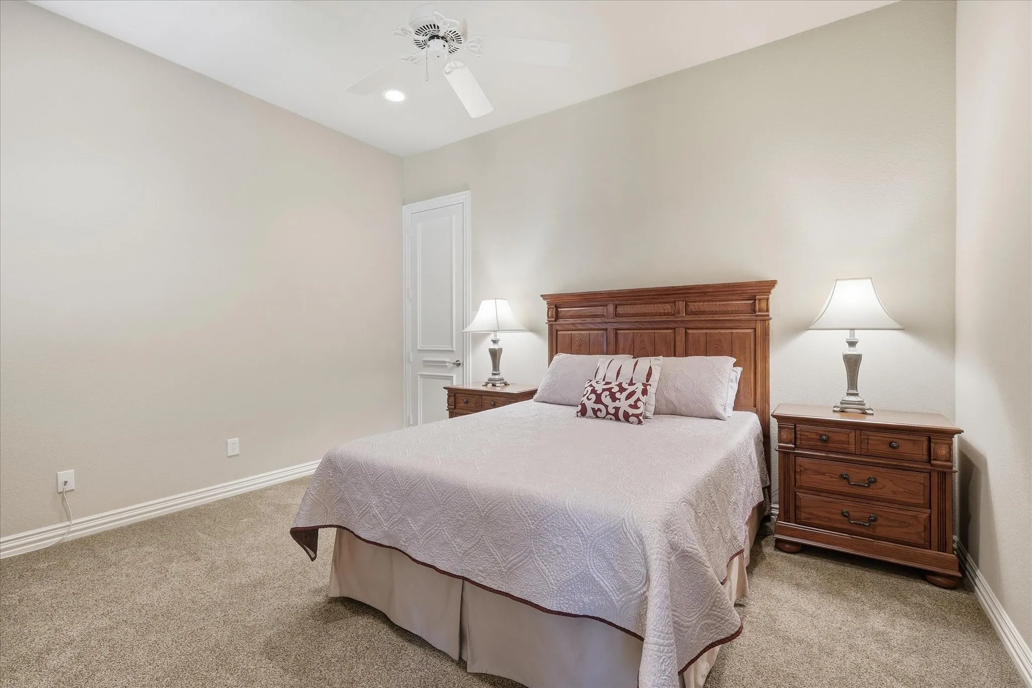 Carpeted flooring, vaulted ceiling, ceiling fan with integrated lighting, and a paneled interior door