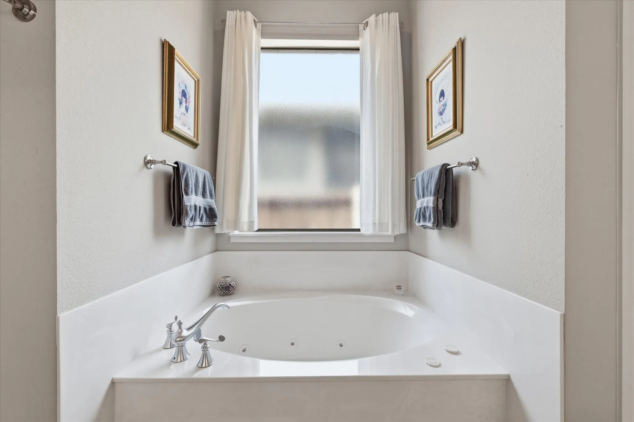 Built-in soaking tub with polished chrome fixtures, integrated jets, and a frosted window