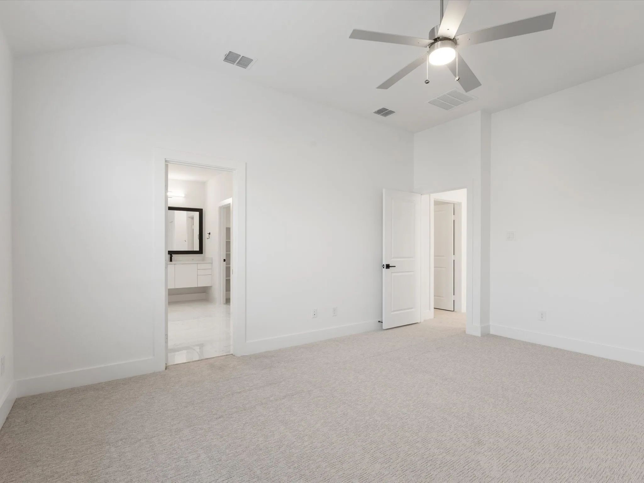 Primary bedroom with carpet, a ceiling fan, ensuite bath, and vaulted ceiling