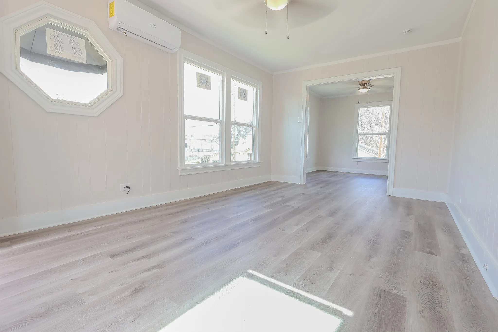 Wood-finish flooring throughout, multiple windows providing natural light, and a ceiling fan