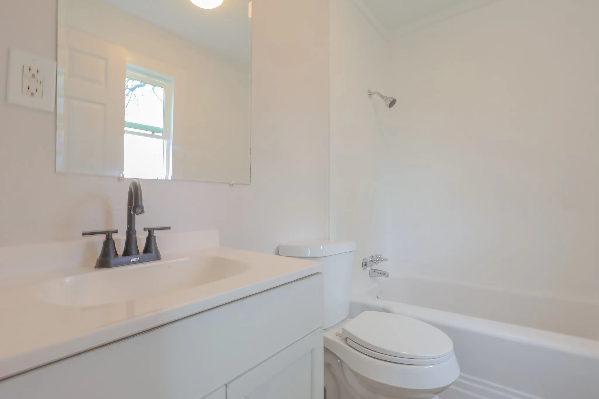 Vanity with a single basin sink, matte black faucet, and frameless rectangular mirror